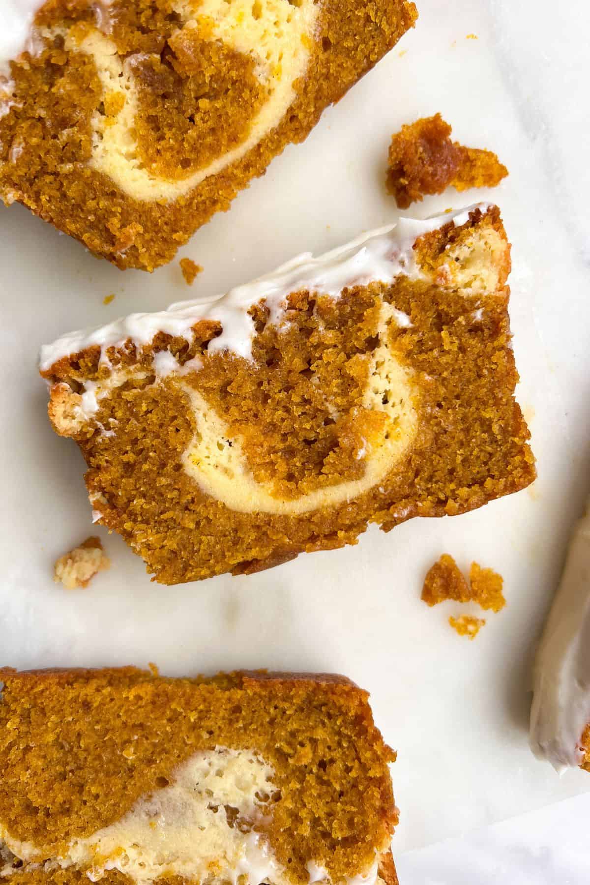 Slice of pumpkin bread with cream cheese frosting on a platter.