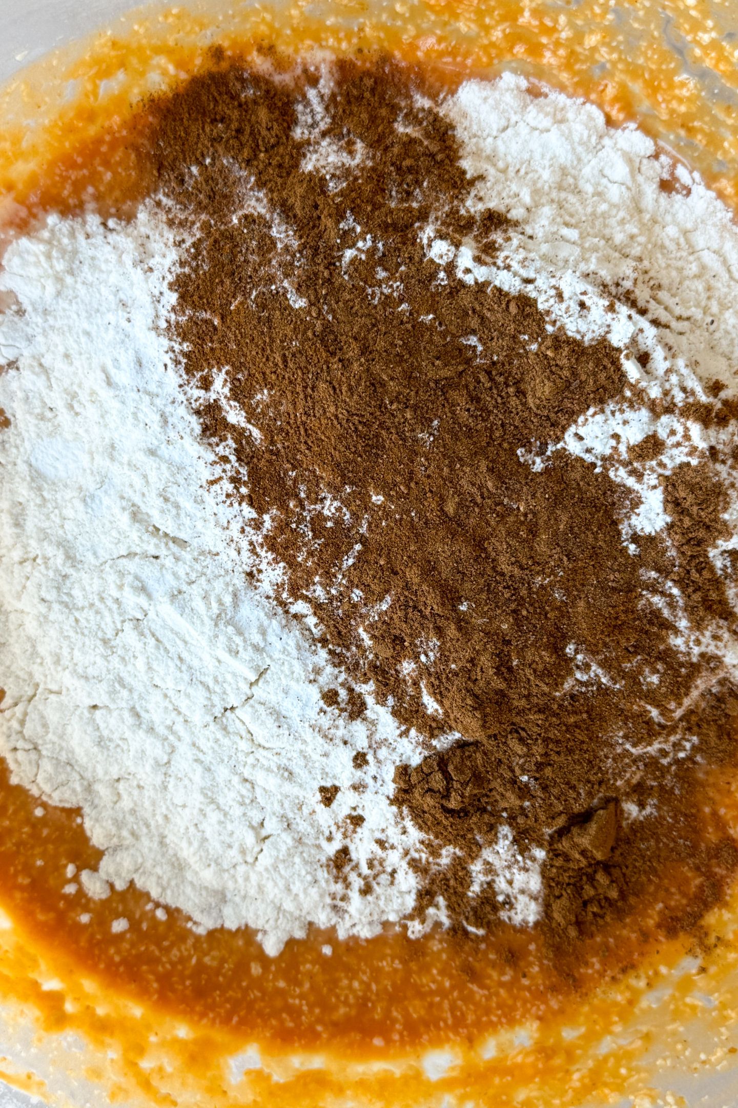 Adding dry ingredients to the wet in the mixing bowl.