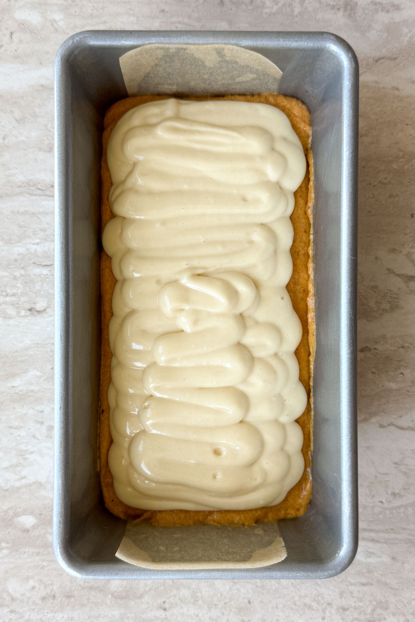 Adding cheesecake layer on top of pumpkin bread batter to the loaf pan.