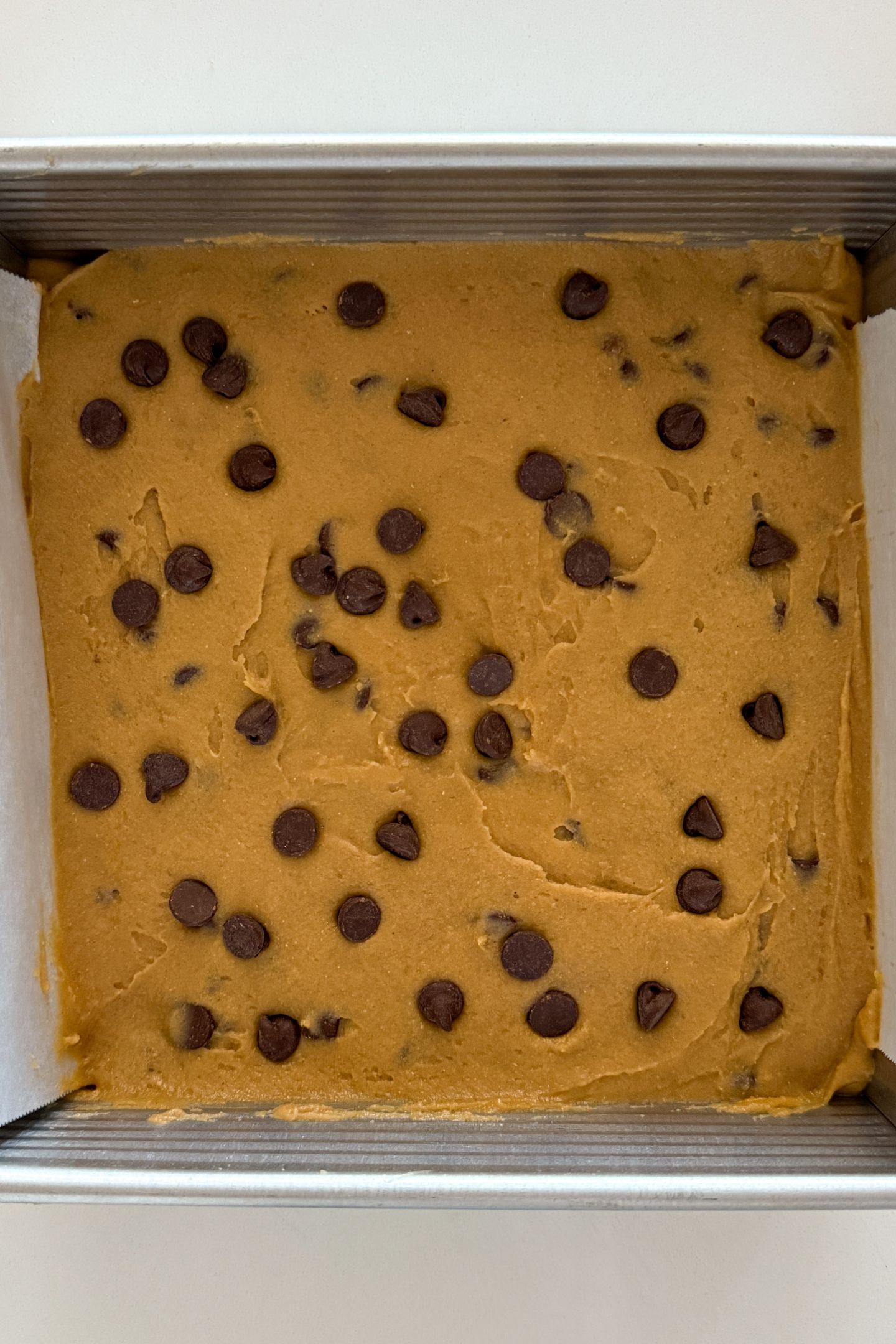 Blondie batter transferred to a prepared pan and spread in an even layer.