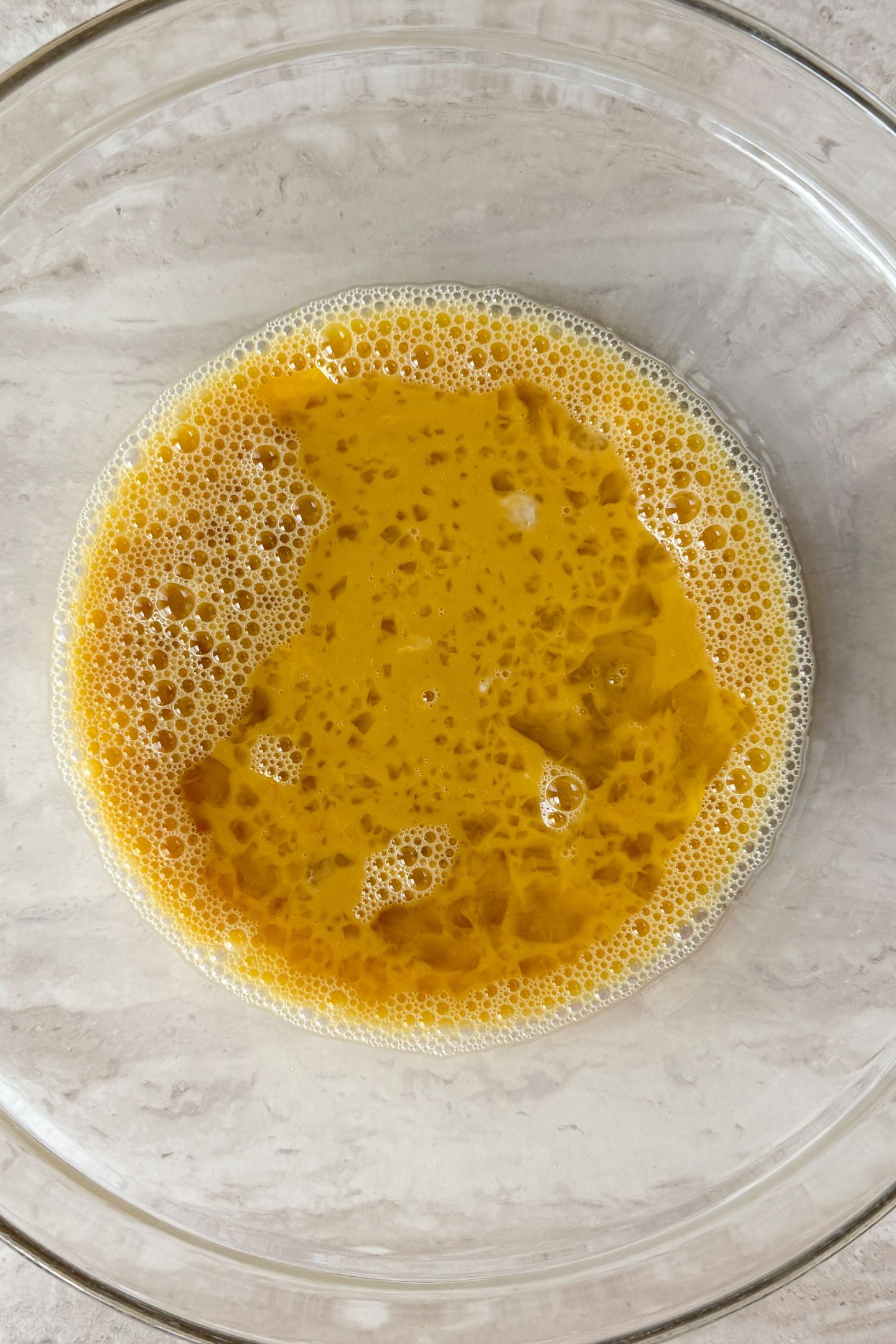 Eggs and milk whisked together in a mixing bowl.