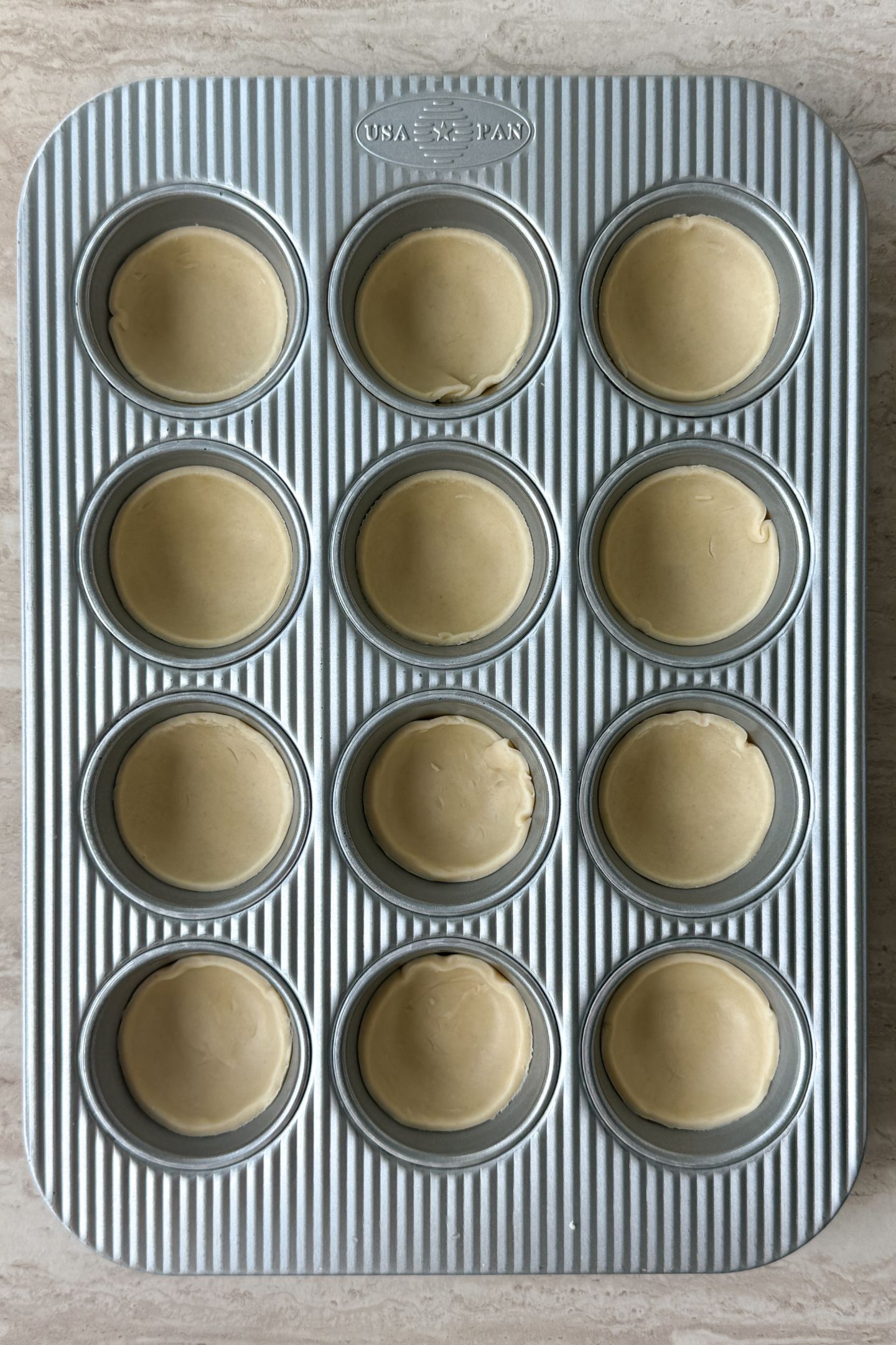 Cut out pie dough in the muffin molds.