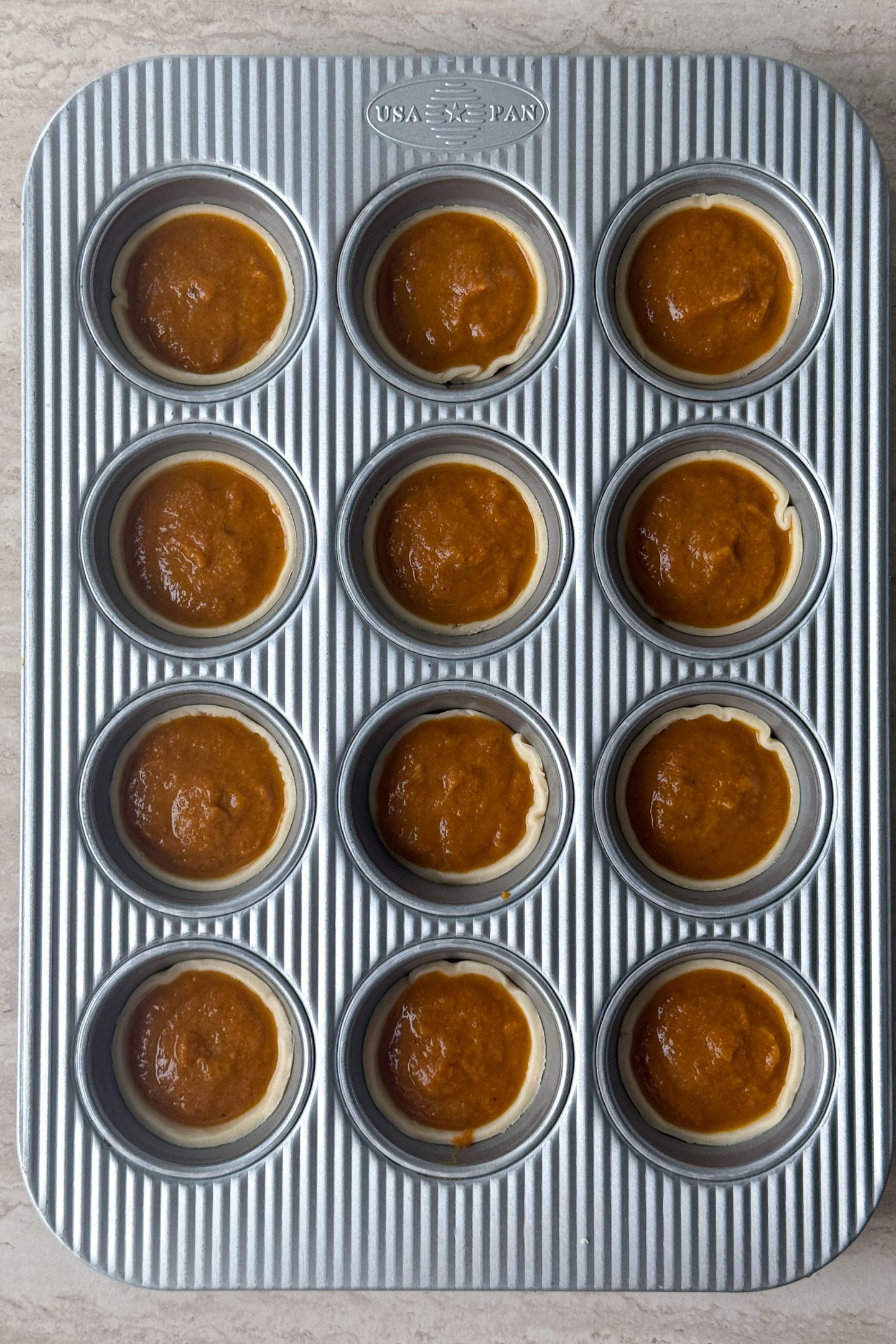 Pumpkin pie filling added in the pie crusts in the muffin tin.