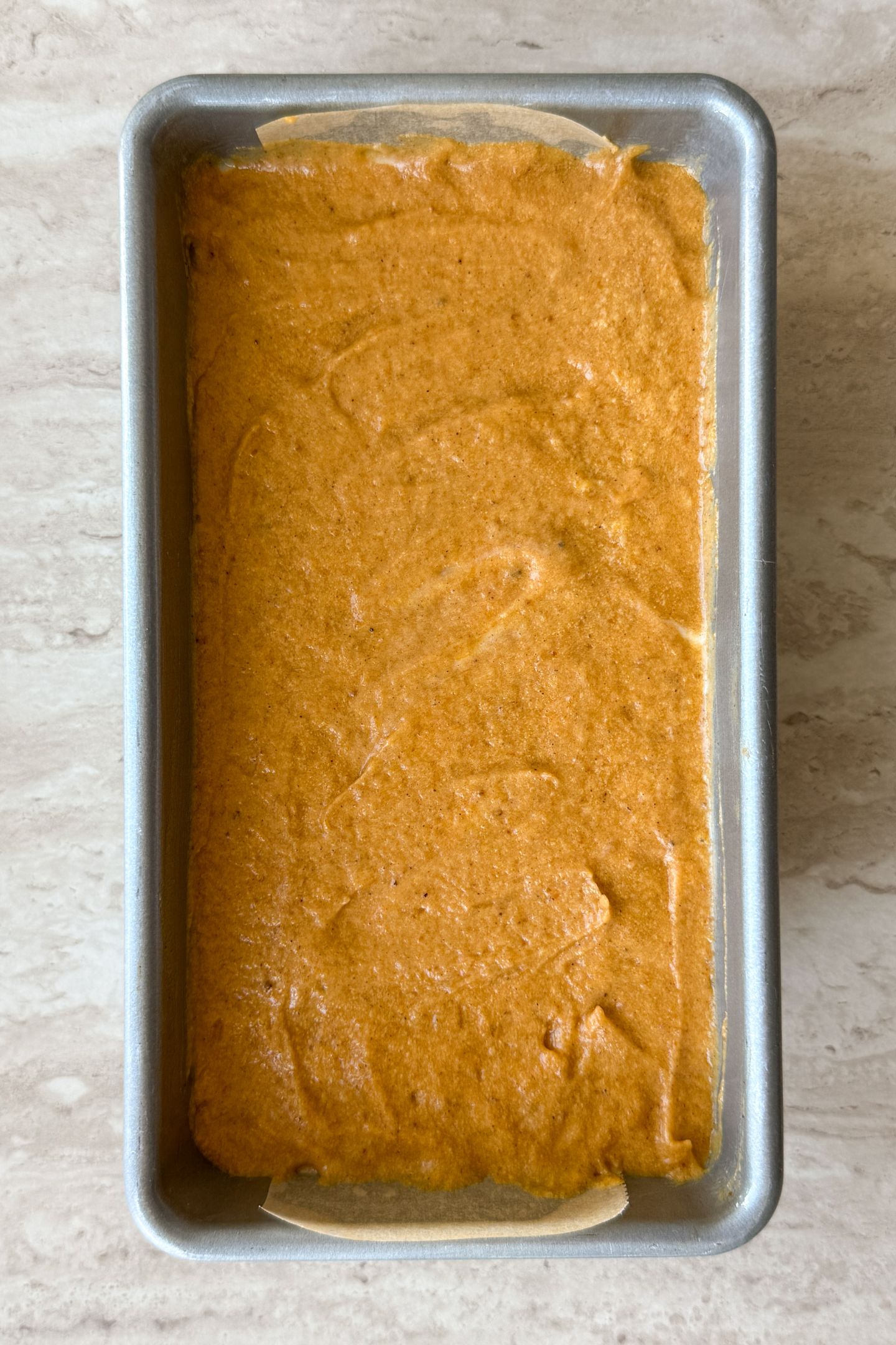 Adding all layers on top of pumpkin bread batter to the loaf pan.