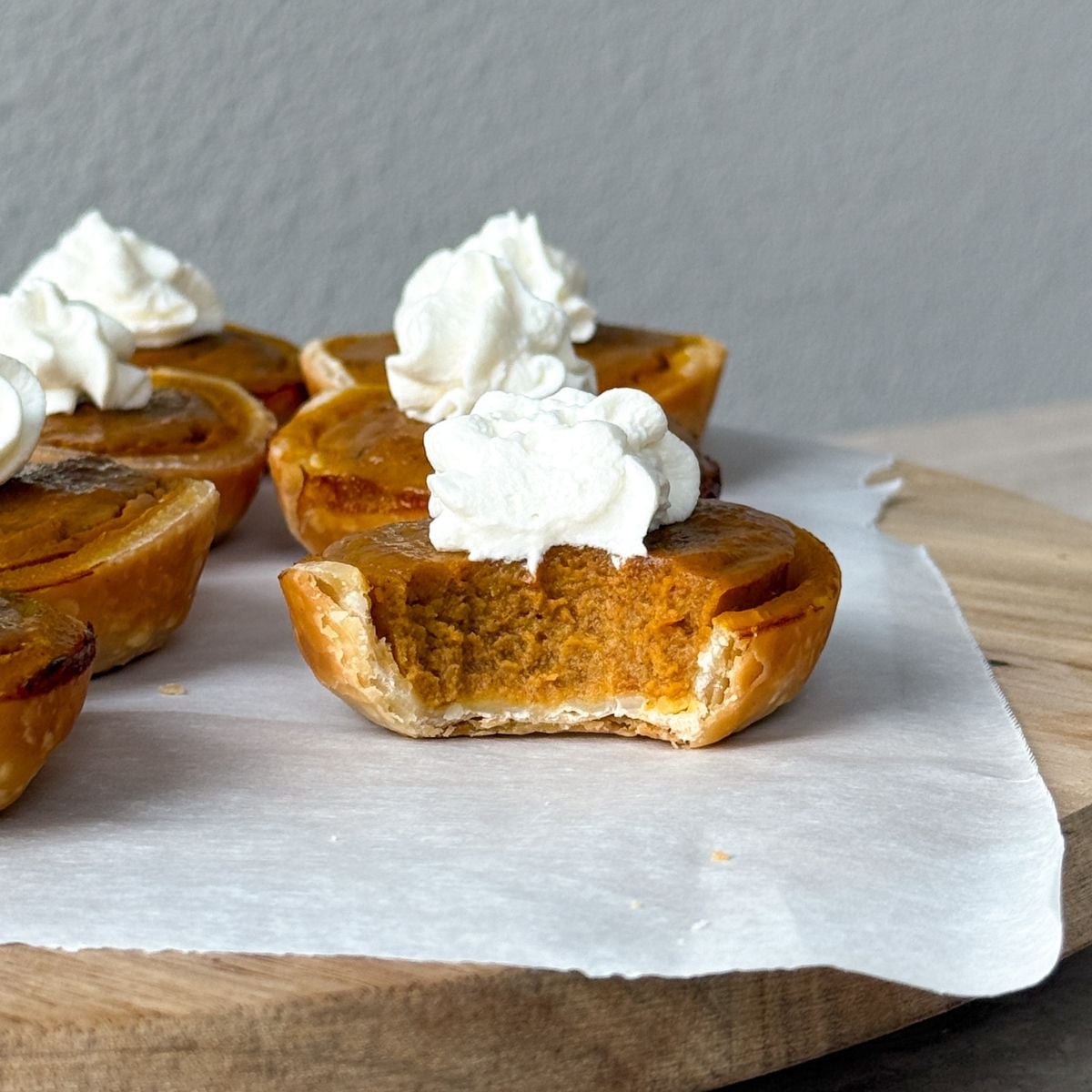 A mini pumpkin pie topped with whipped cream and a bite taken out of it.