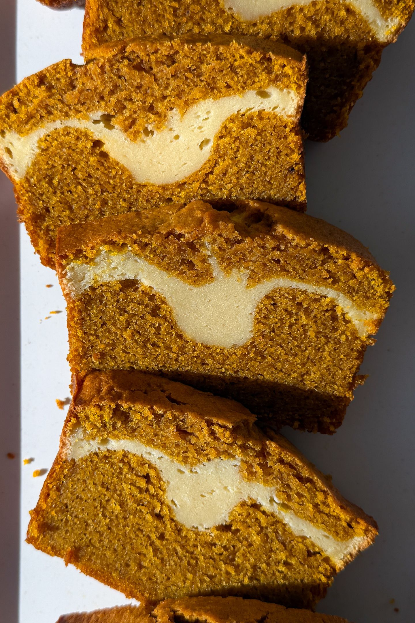 Slices of Pumpkin Cheesecake Swirl Bread on a platter.