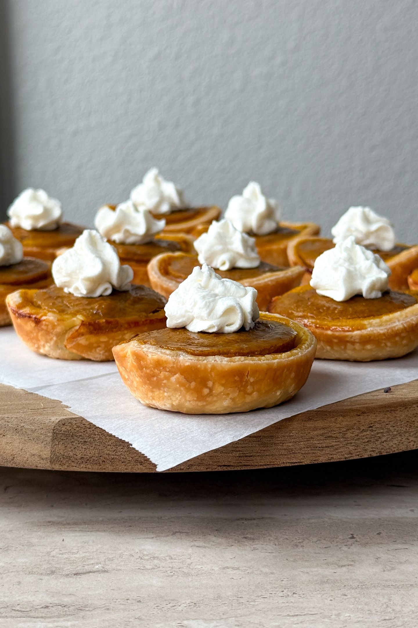 Mini Pumpkin Pies on a platter topped with whipped cream.