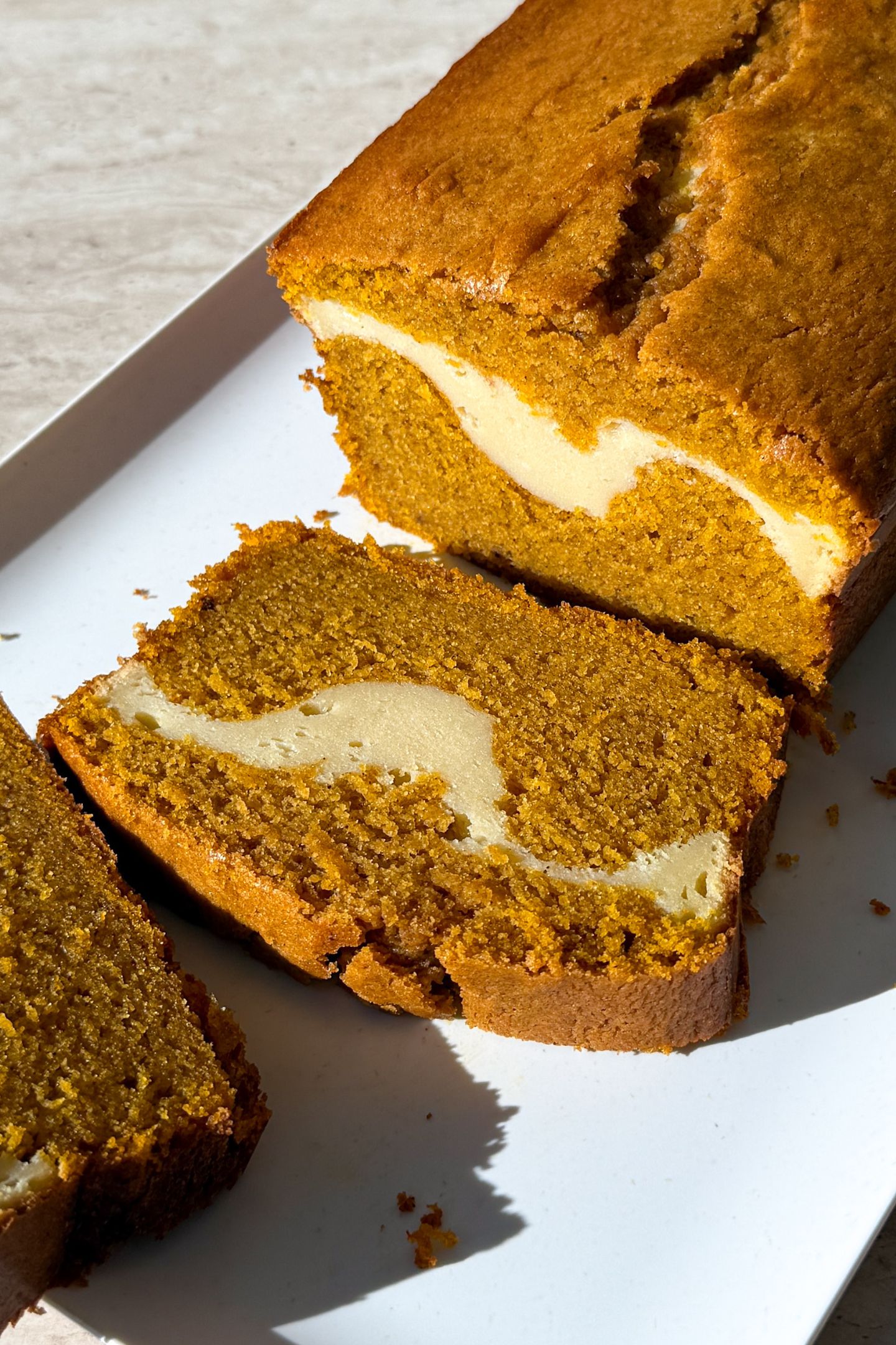 Slicing the pumpkin bread with the cheesecake layer in the middle.