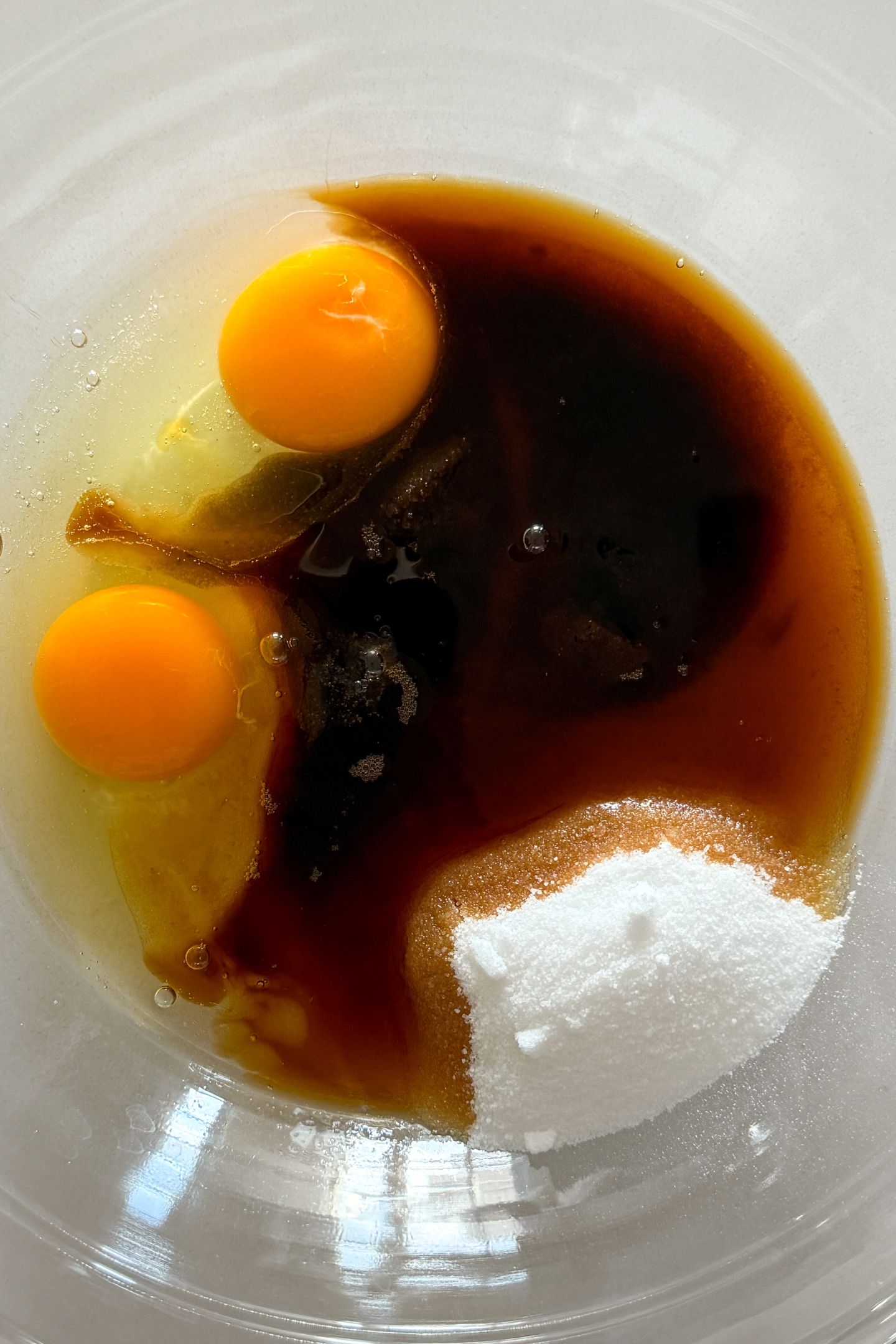 Sugars and eggs in a bowl with the vanilla extract and liquid coffee.