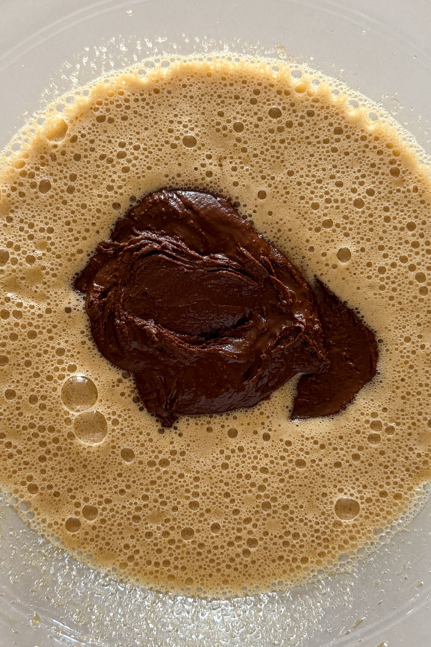 Wet ingredients combined in a bowl with the melted chocolate and butter added in the middle.