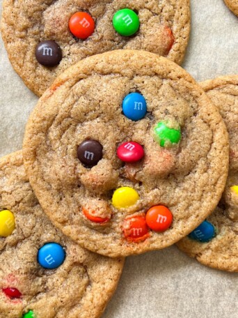 Stack of M and M cookies on a baking tray.