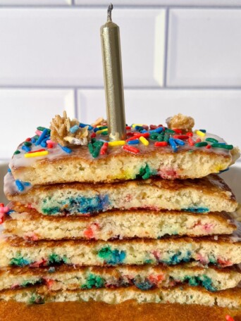 Birthday Cake Pancakes topped with a glaze, sprinkles and a candle.