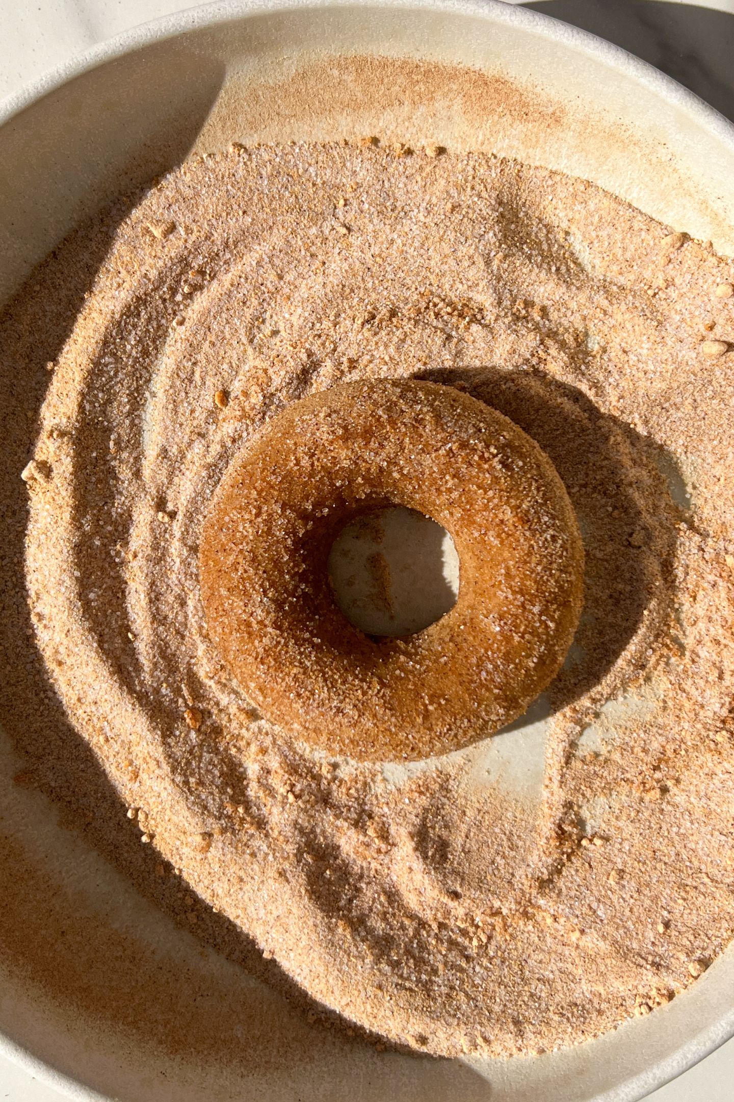 Donut in a bowl with cinnamon and sugar mixture