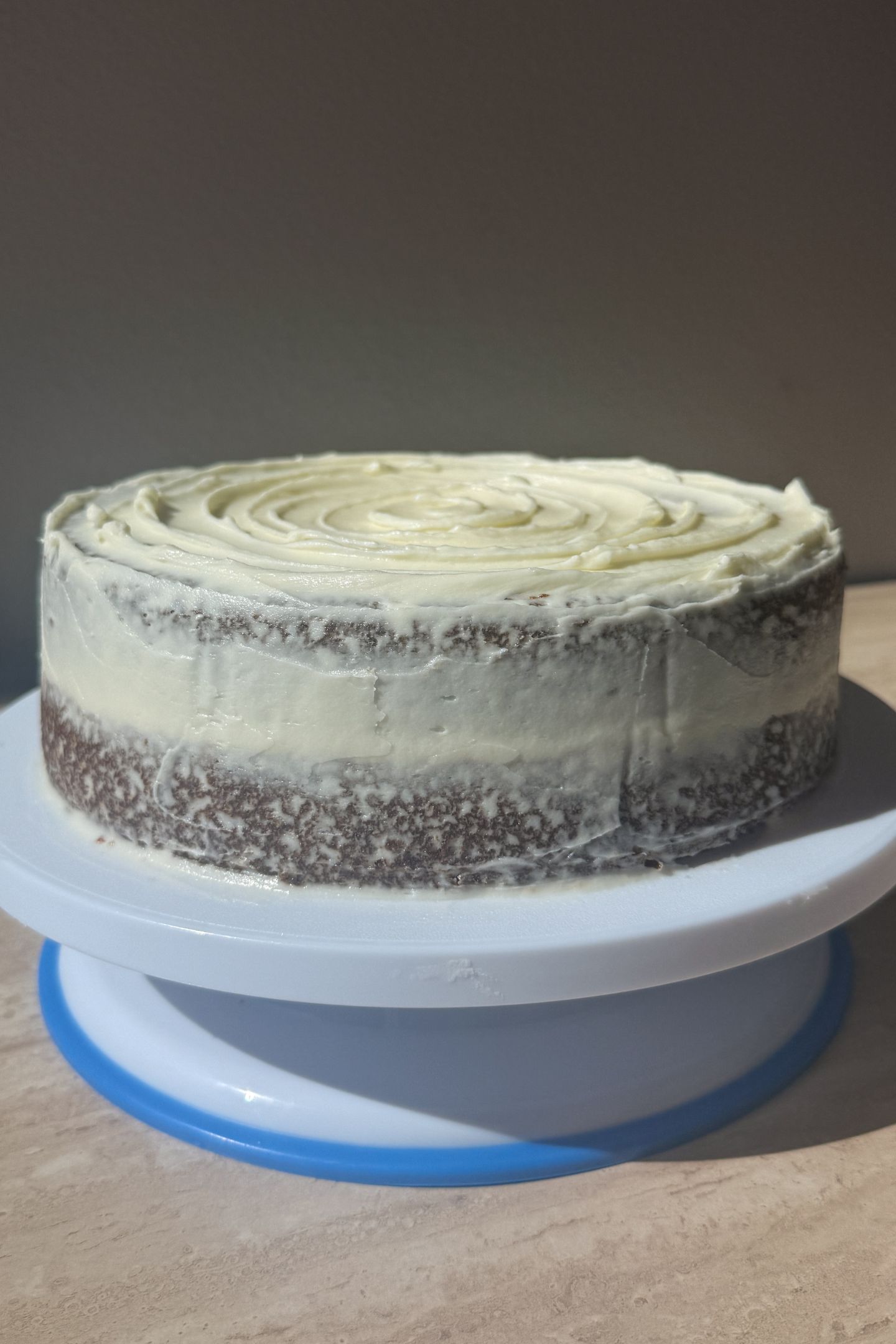 A frosted two layer carrot cake on a cake stand.