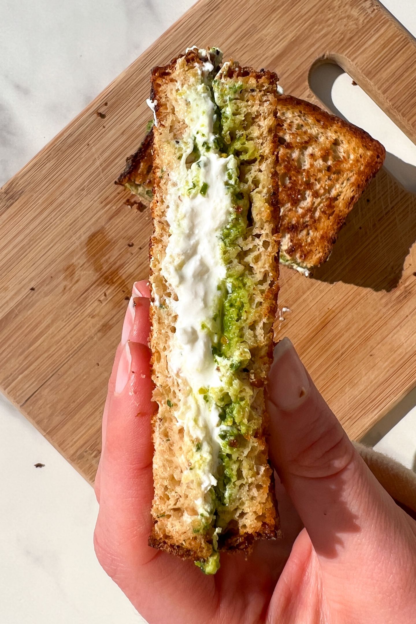 Holding a Burrata Sandwich with pesto.