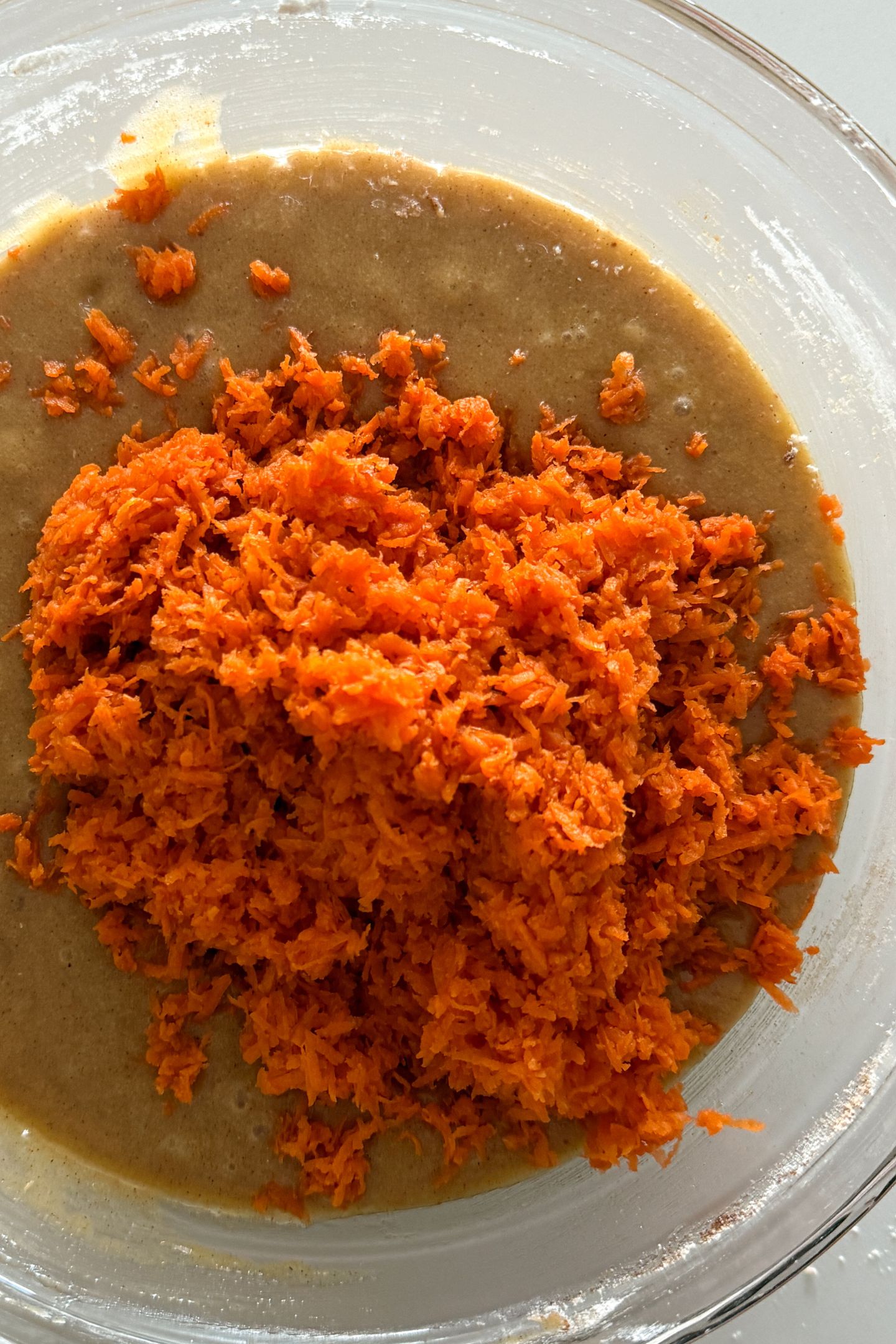 Adding the shredded carrots to the cake batter.