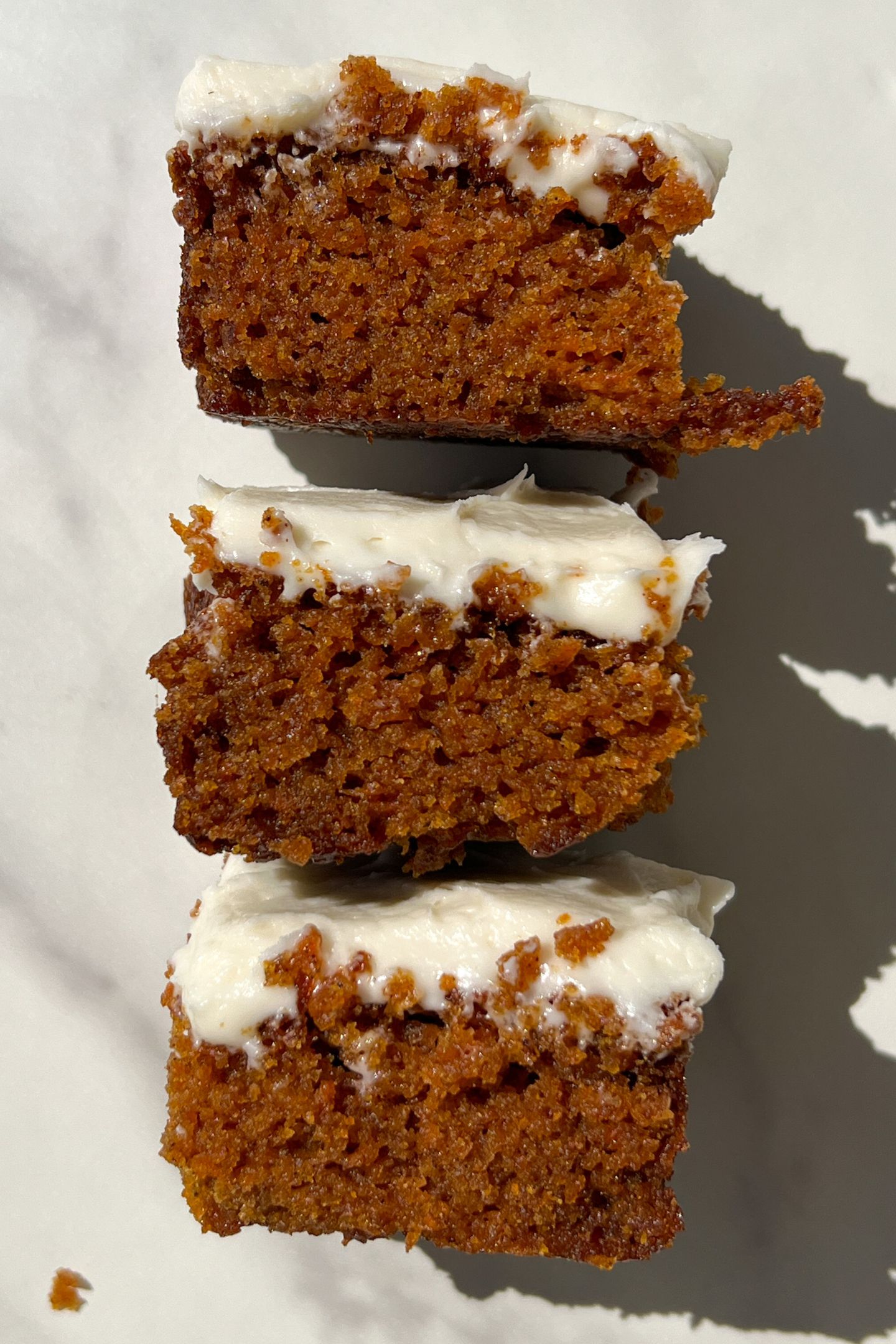 Slices of Gluten Free Carrot Cake topped with a cream cheese frosting.