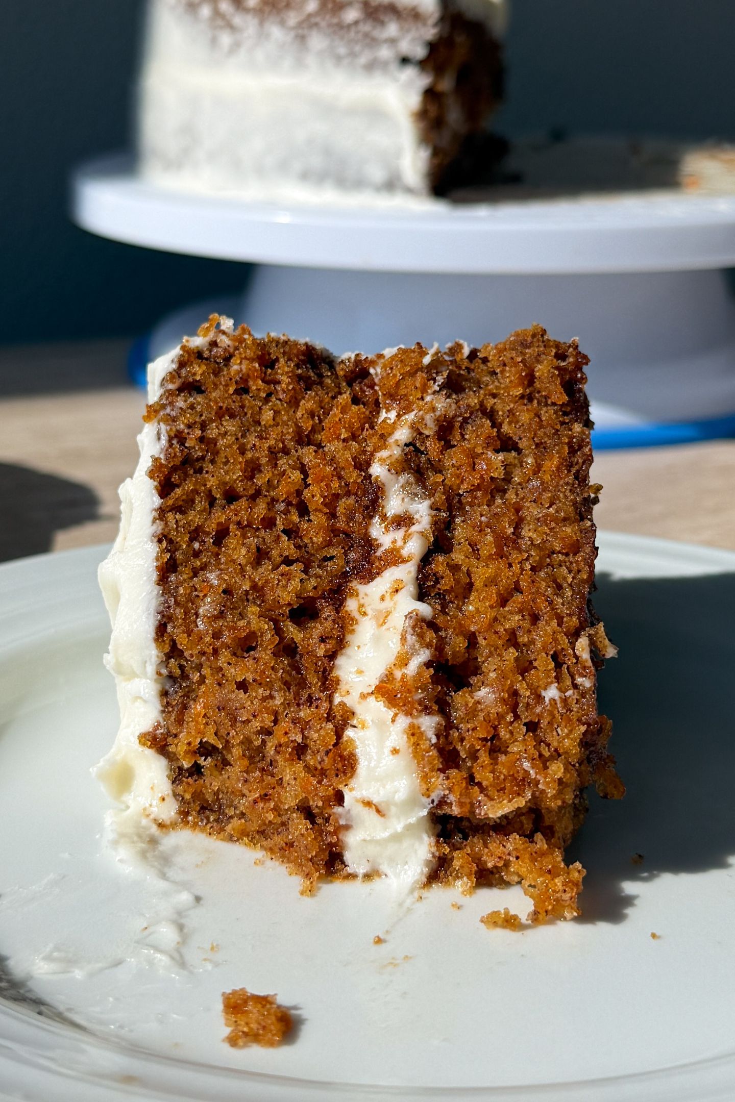 A slice of frosted gluten-free carrot cake on a plate.