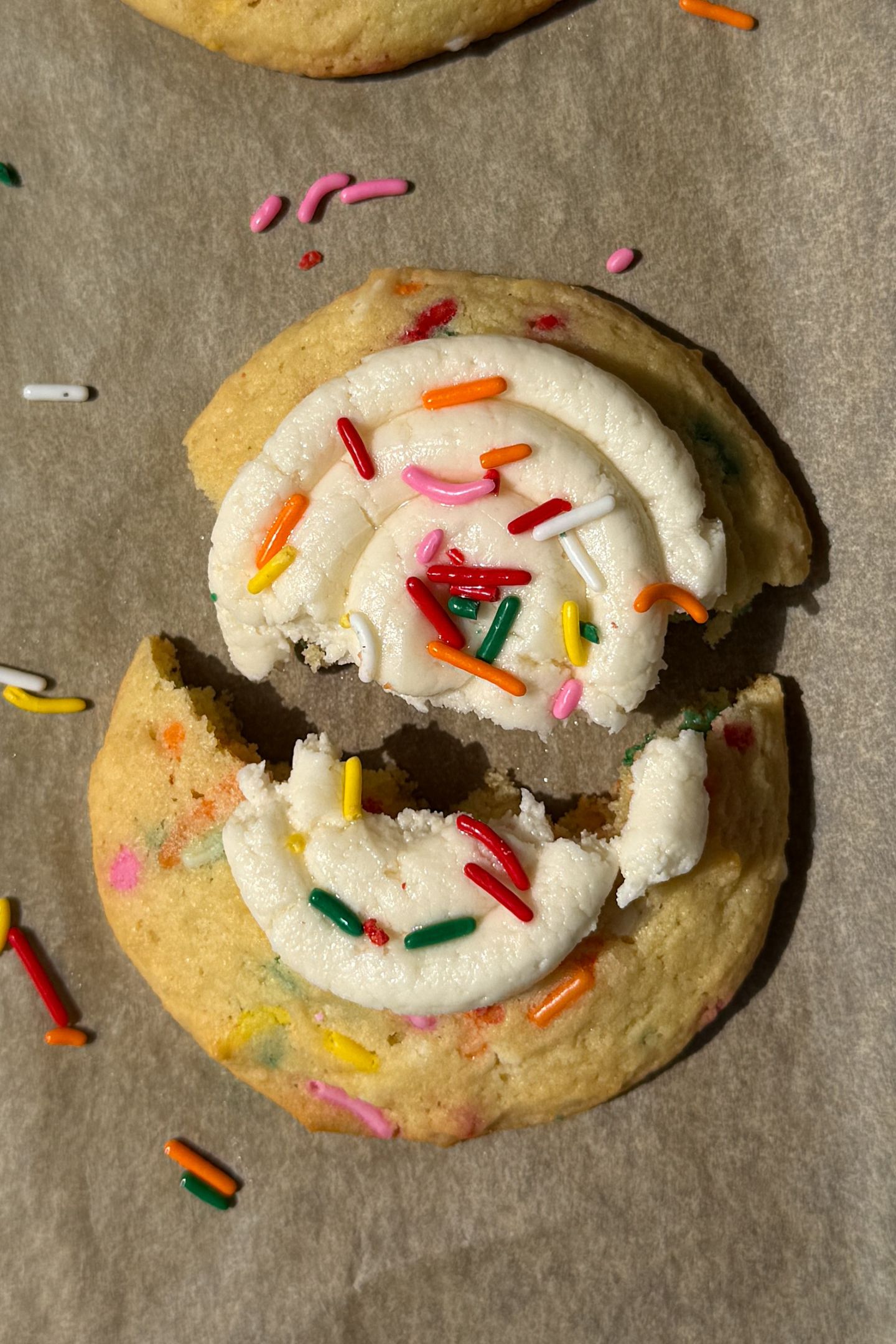 A funfetti sugar cookie topped with frosting that has been broken apart.