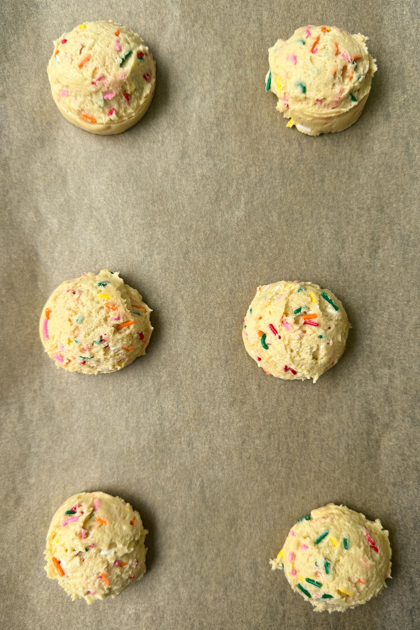 Cookie dough portioned on a baking sheet lined with parchment paper.