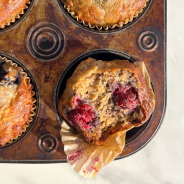 Blackberry Banana Oatmeal Muffins with a bite taken out of it sitting in a muffin tray.