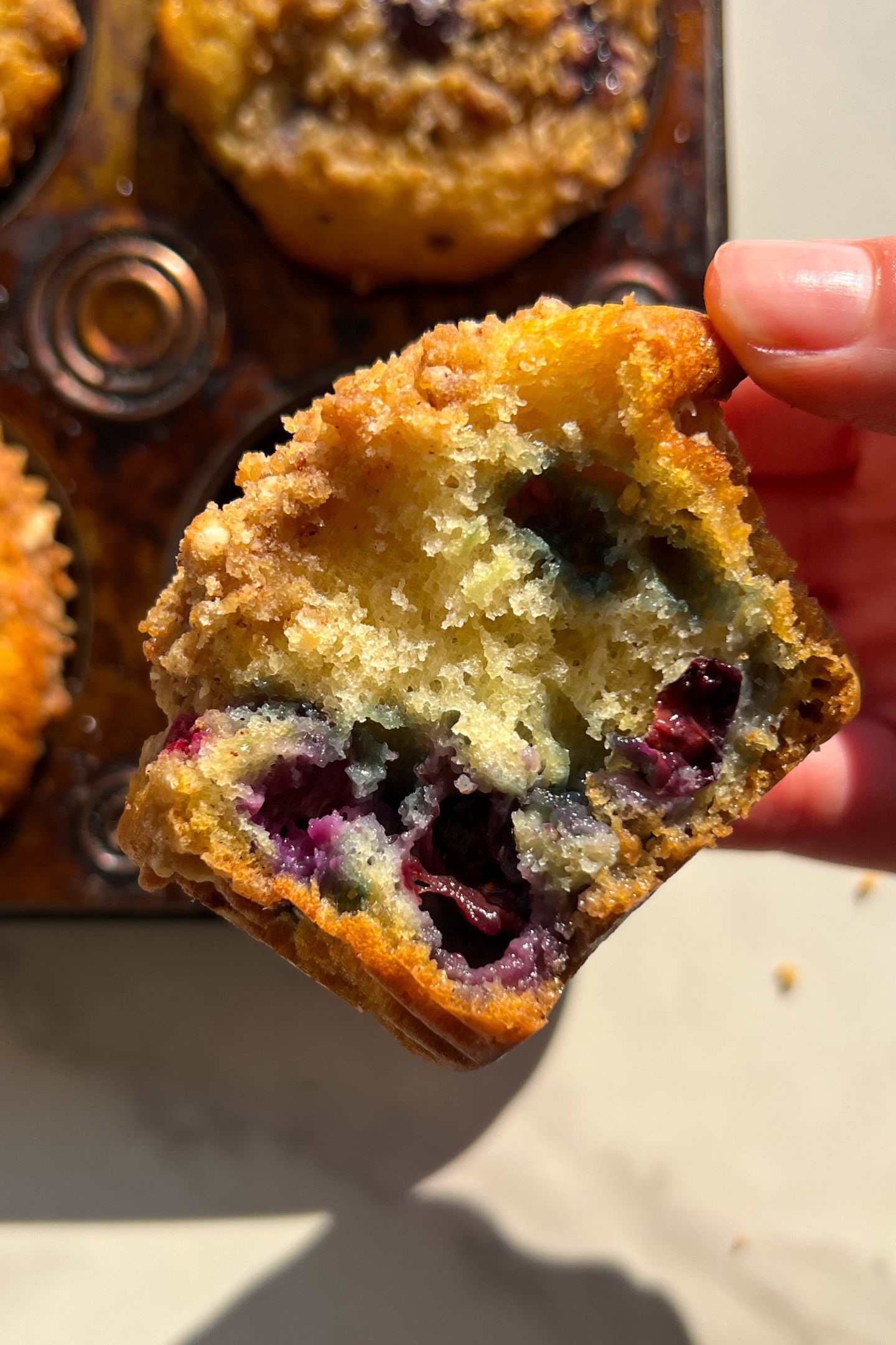 Holding a Blueberry Crumb Muffin in my hand with a bite taken out of it.