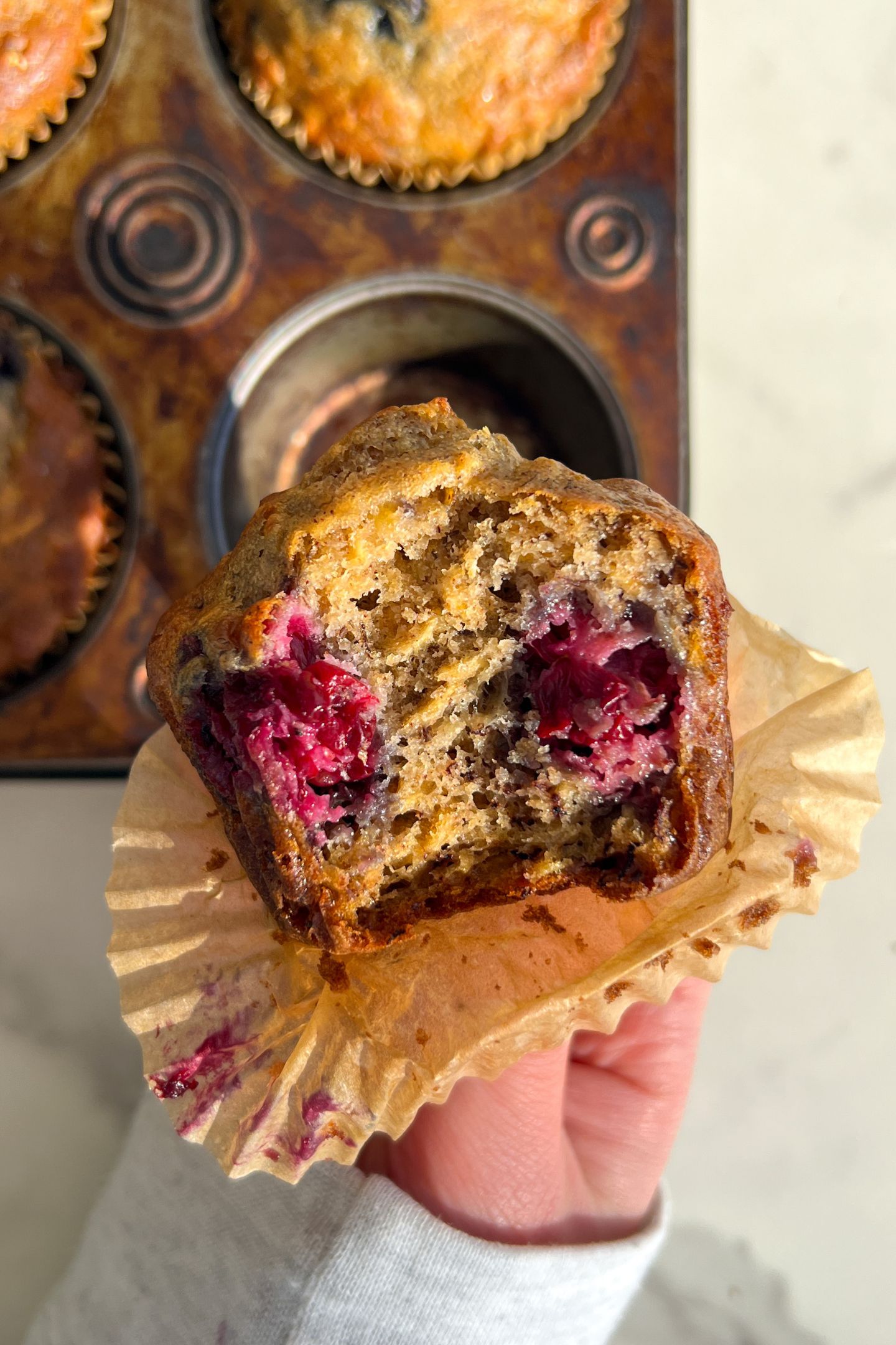 Holding a Banana Blackberry Muffin in my hand with a bite taken out of it.