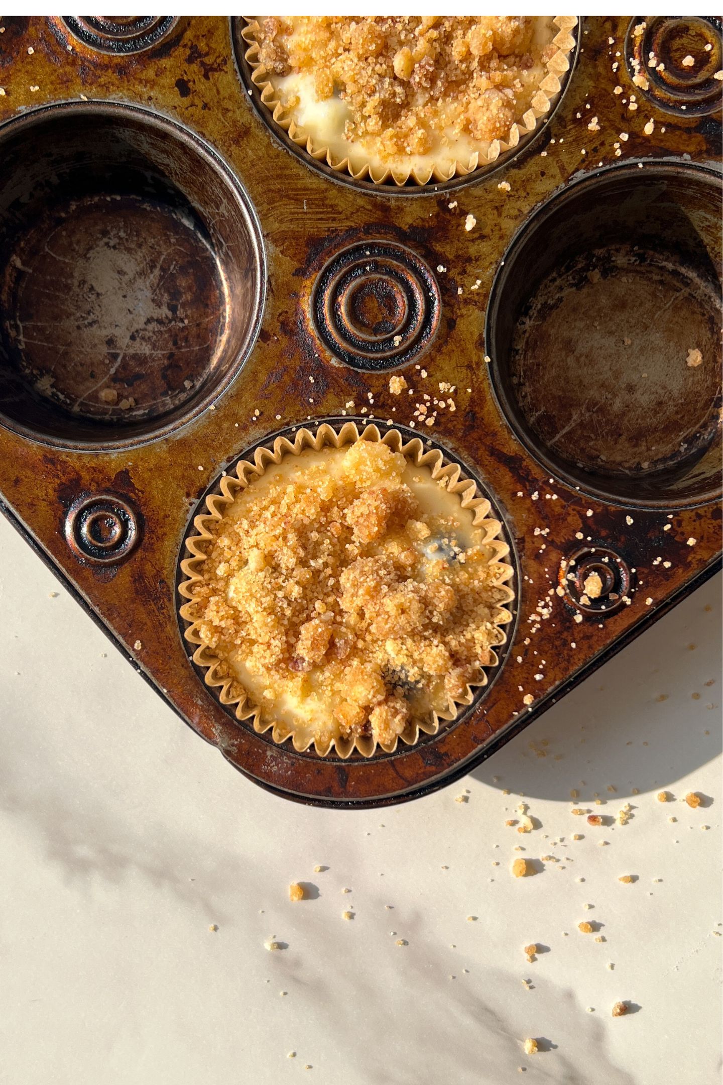 Batter in muffin liners topped with crumble.