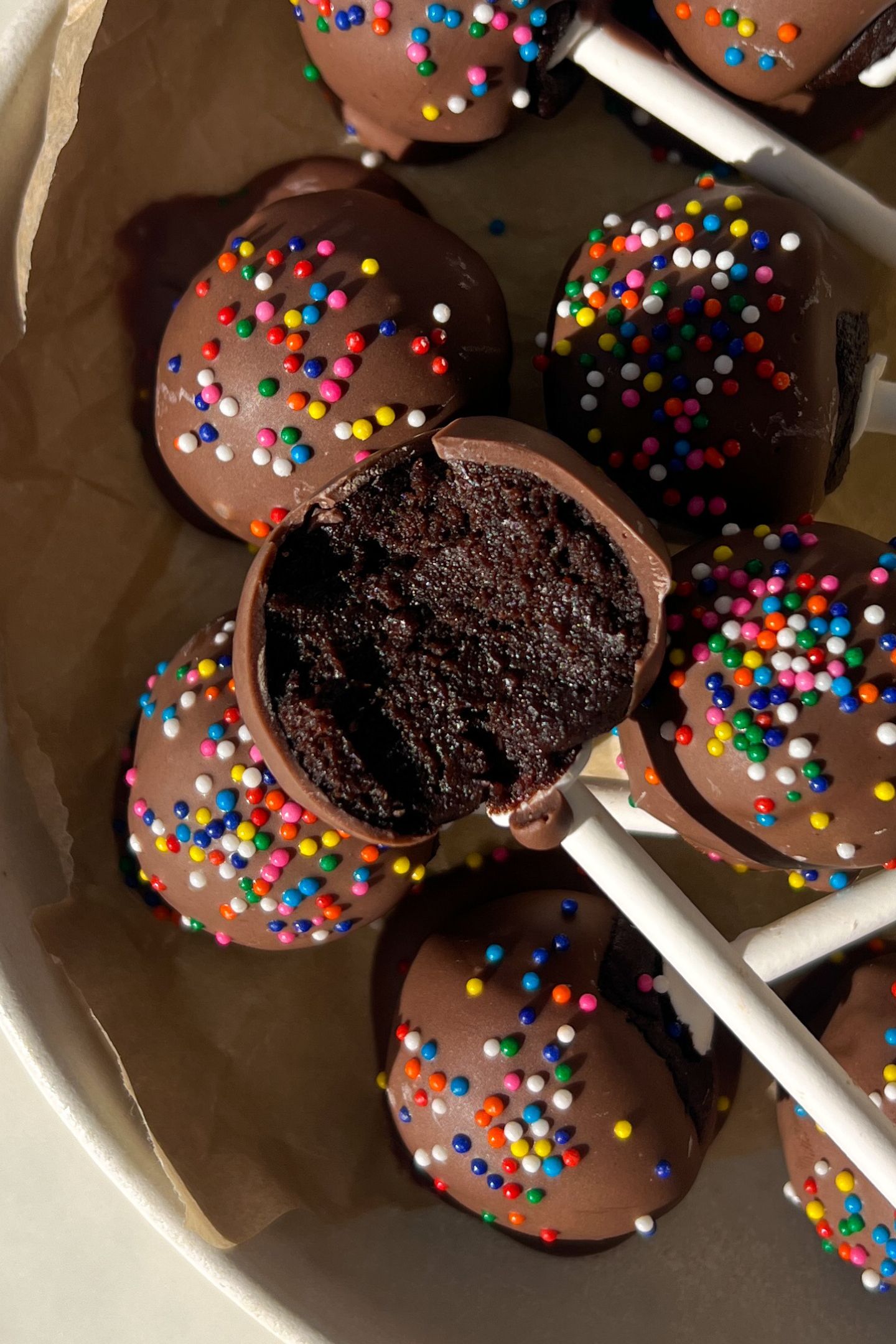 Chocolate cake pop with a bite taken out of it.