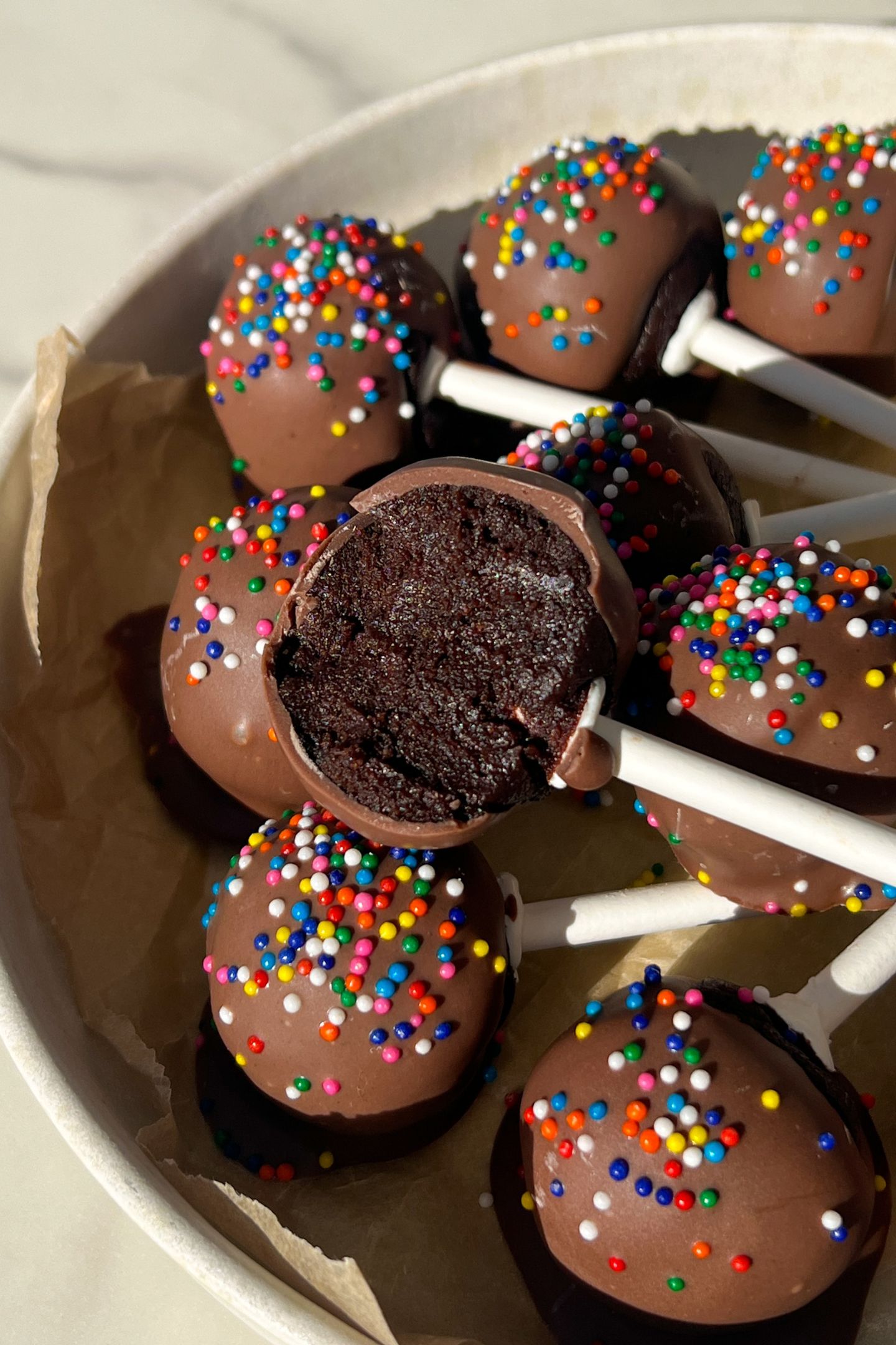 Chocolate cake pop with a bite taken out of it.