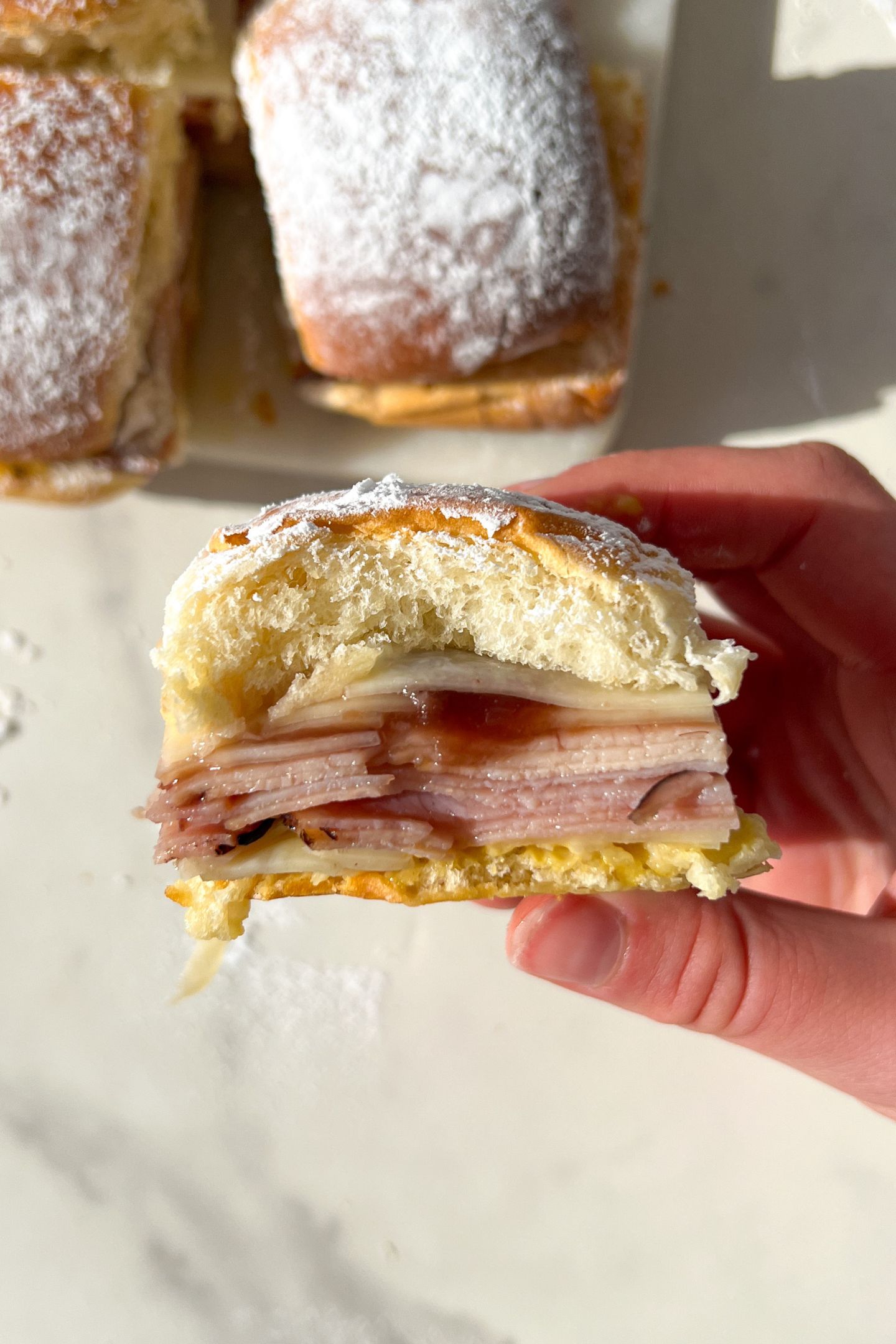 Holding a Monte Cristo Slider that is dusted in powder sugar.