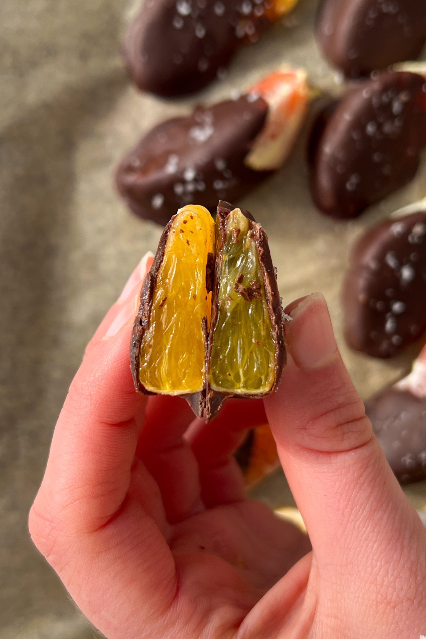 Holding a chocolate orange slice that has been cut in half.