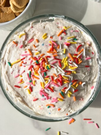Funfetti dip in a bowl, topped with extra sprinkles and served with animal crackers.