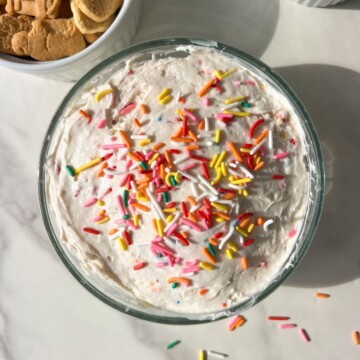Funfetti dip in a bowl, topped with extra sprinkles and served with animal crackers.
