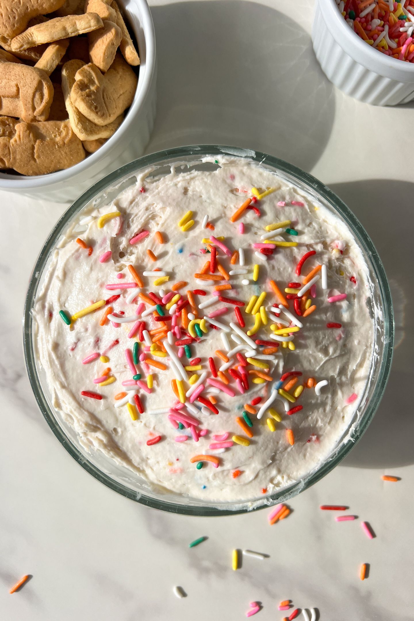 Funfetti dip in a bowl, topped with extra sprinkles and served with animal crackers.