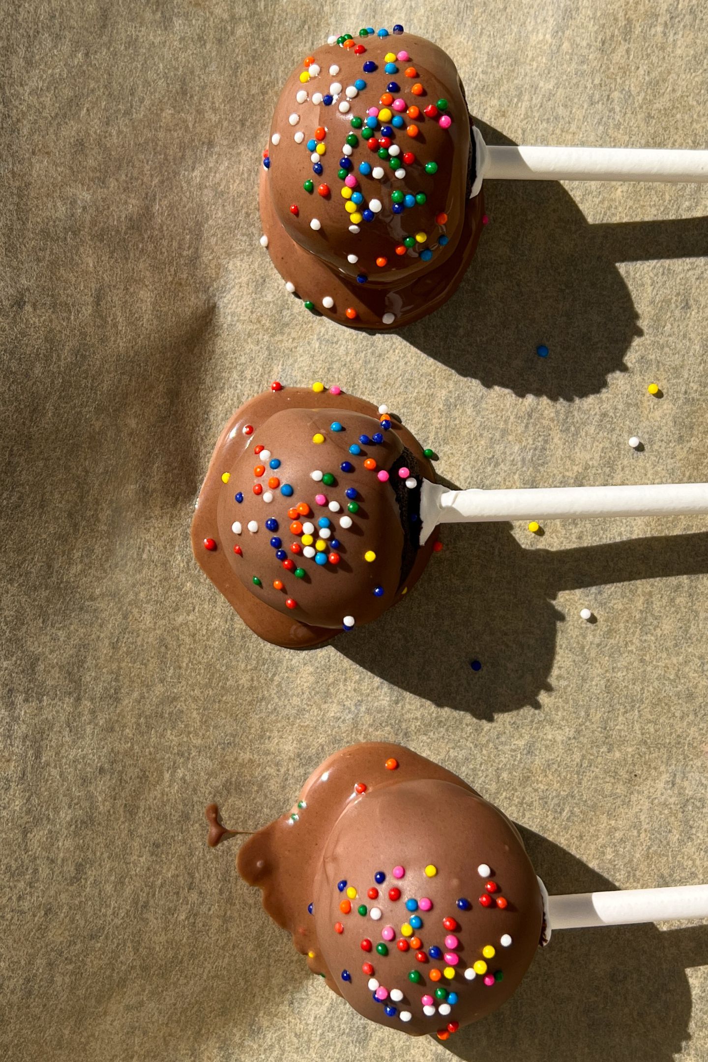 Dipped cake pops with sprinkles on a baking sheet lined with parchment paper.