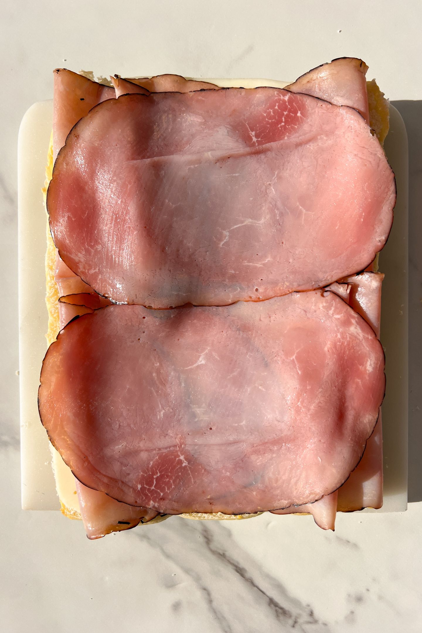 Ham slices placed on top of the swiss cheese.