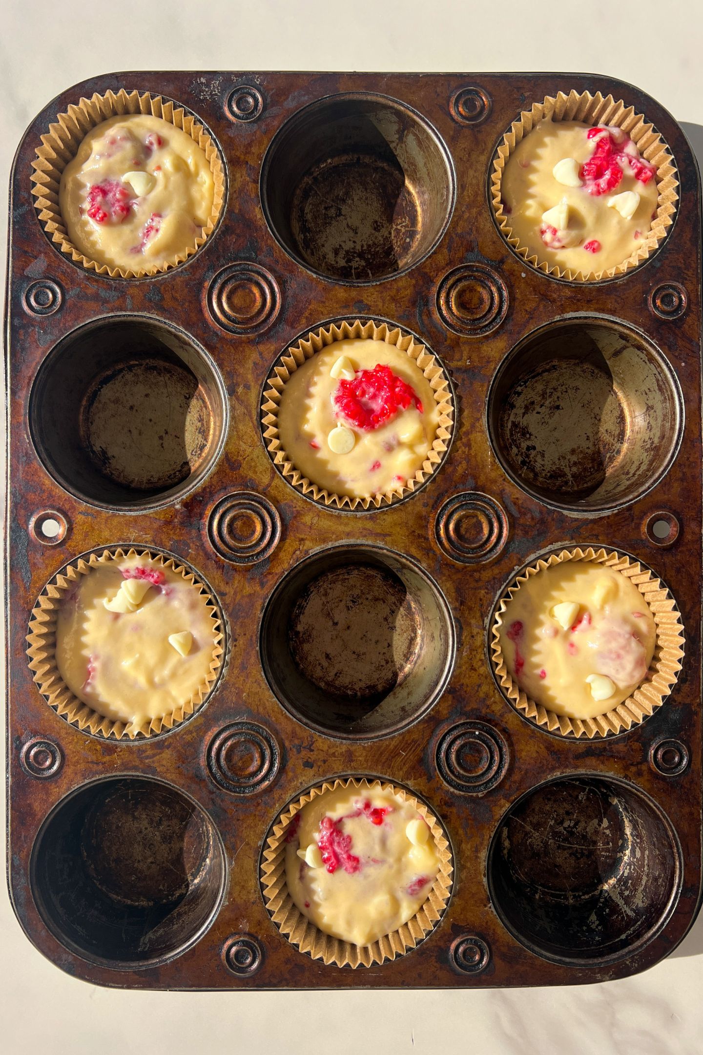 Muffin batter in muffin liners in a muffin tin.