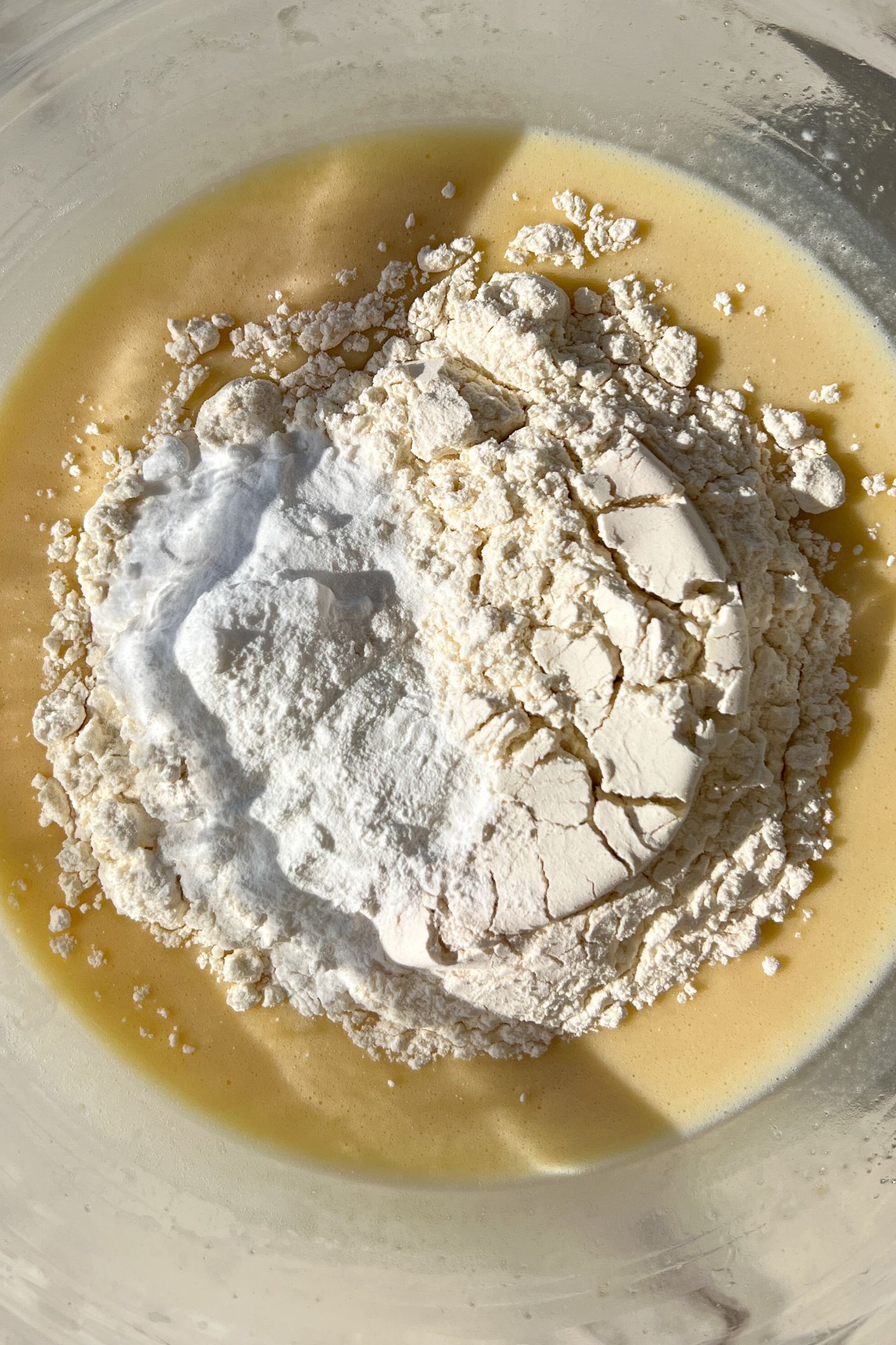 Adding dry to the wet ingredients in a mixing bowl.