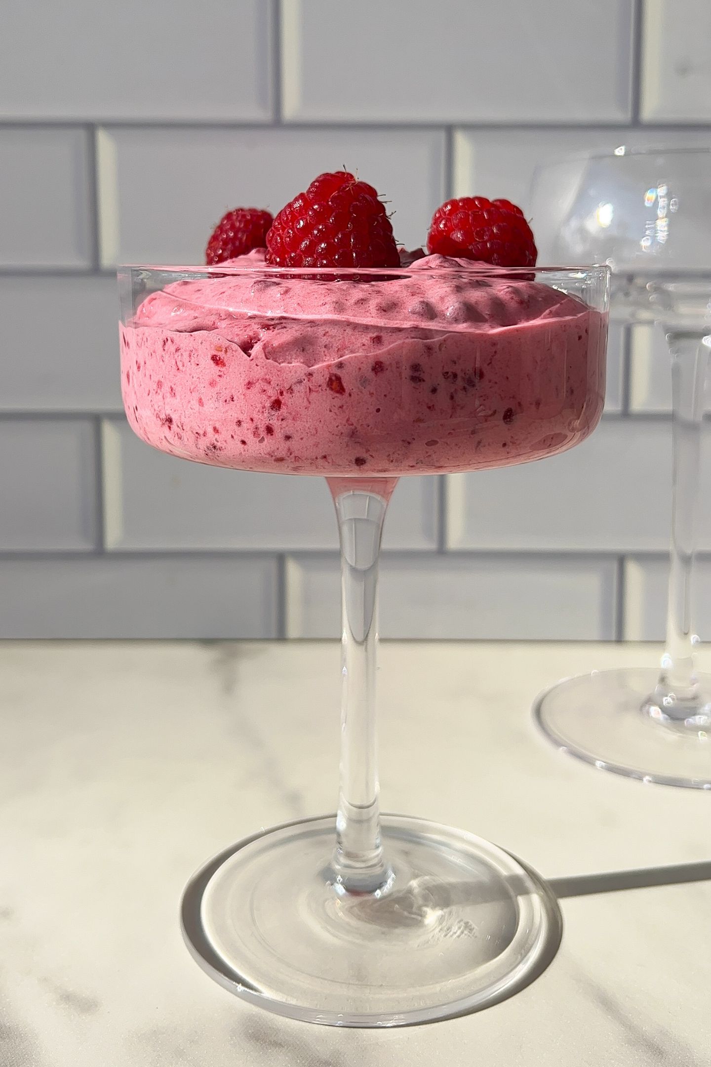 Whipped raspberry cream in a cup with fresh raspberries.
