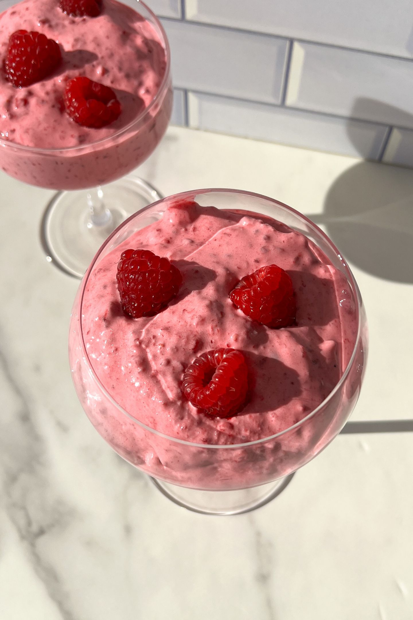 Whipped raspberry cream in a cup with fresh raspberries.