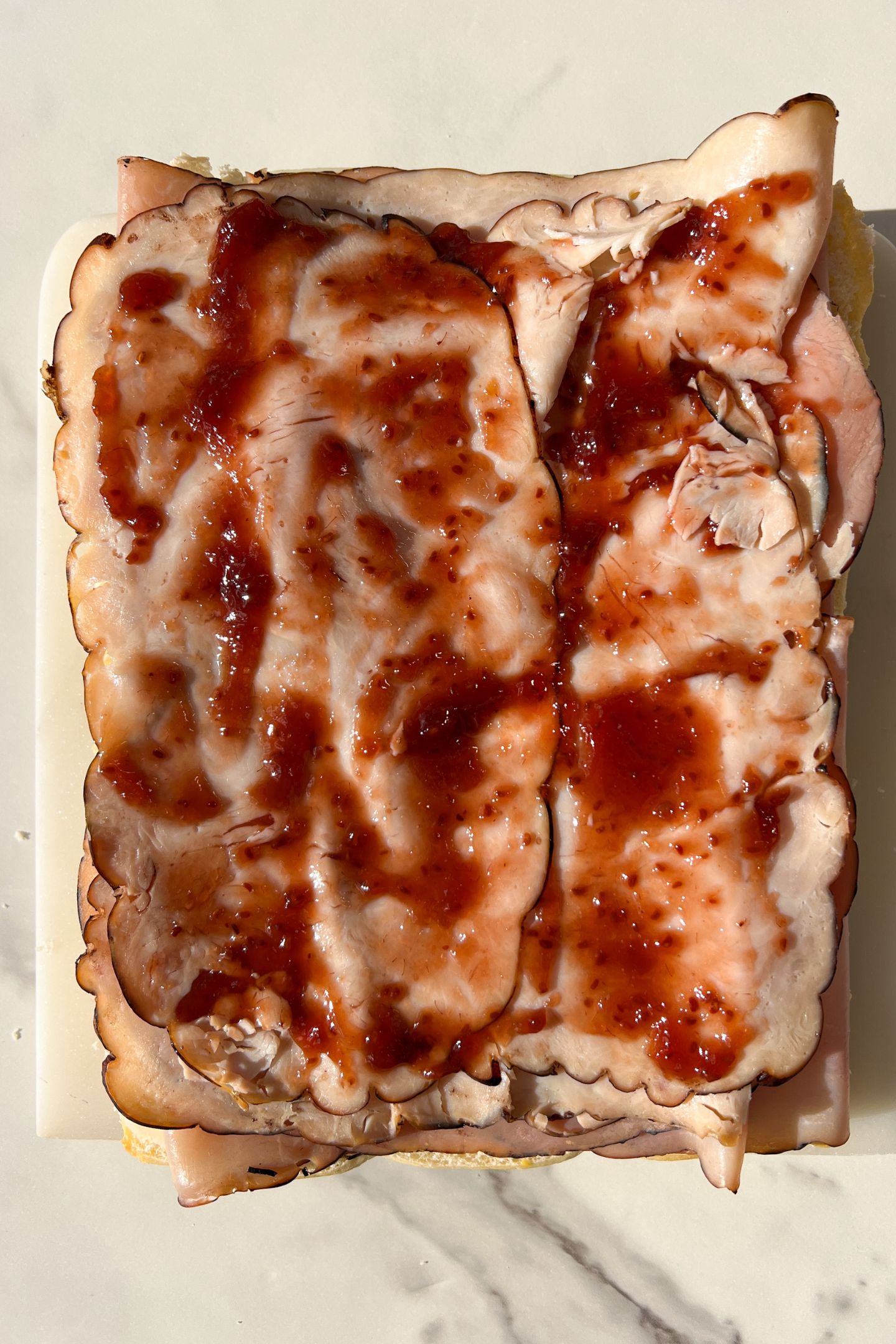 Raspberry jam spread over the deli meat.