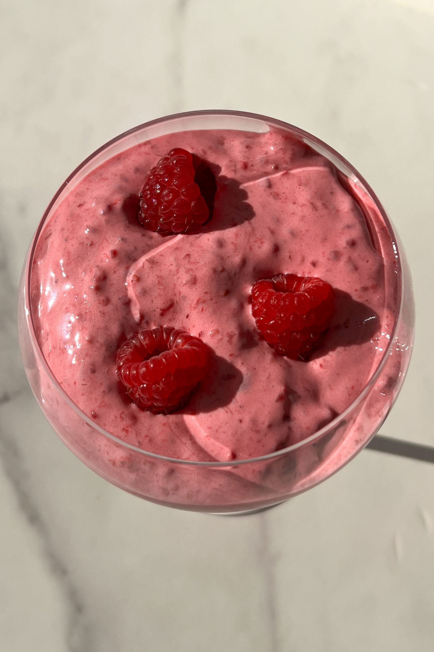 Raspberry Whipped Cream served in a glass with fresh raspberries.