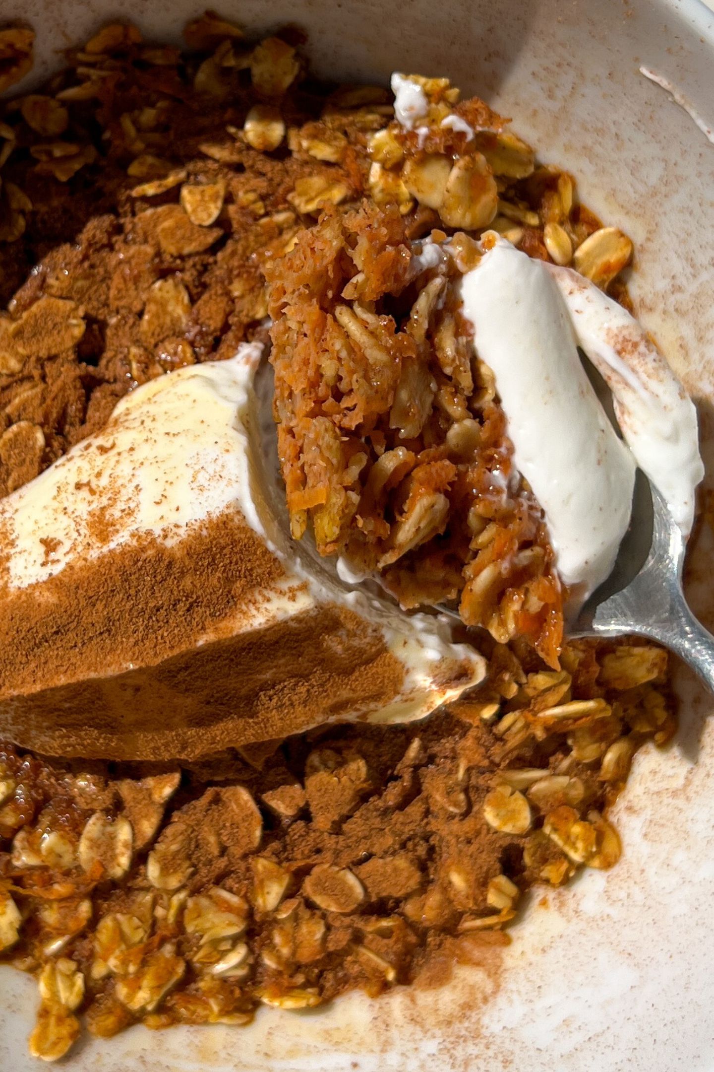 A bowl of carrot cake baked oatmeal with yogurt and cinnamon.