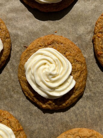 Frosted Carrot Cake Cookies on a baking sheet lined with parchment paper.