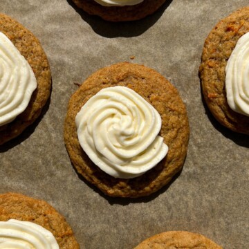 Frosted Carrot Cake Cookies on a baking sheet lined with parchment paper.
