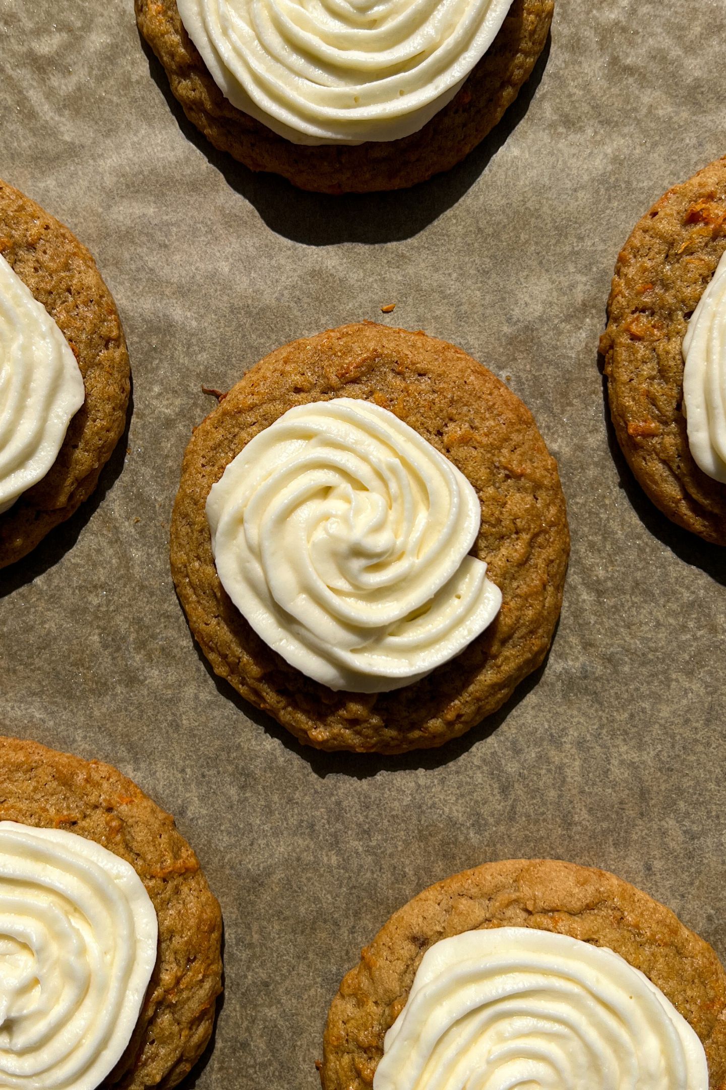 Frosted Carrot Cake Cookies on a baking sheet lined with parchment paper.