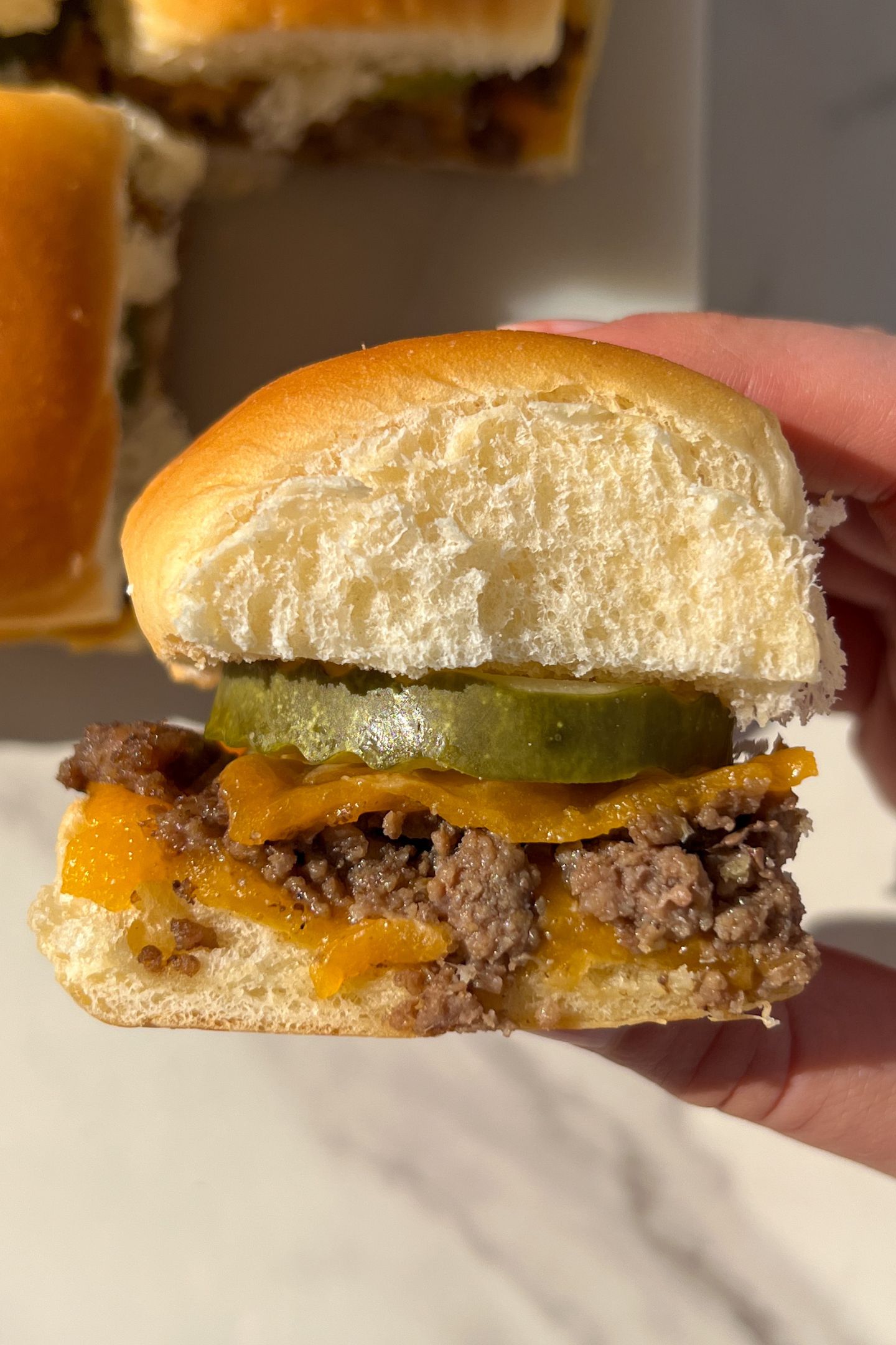 Holding a cheeseburger slider in my hand.