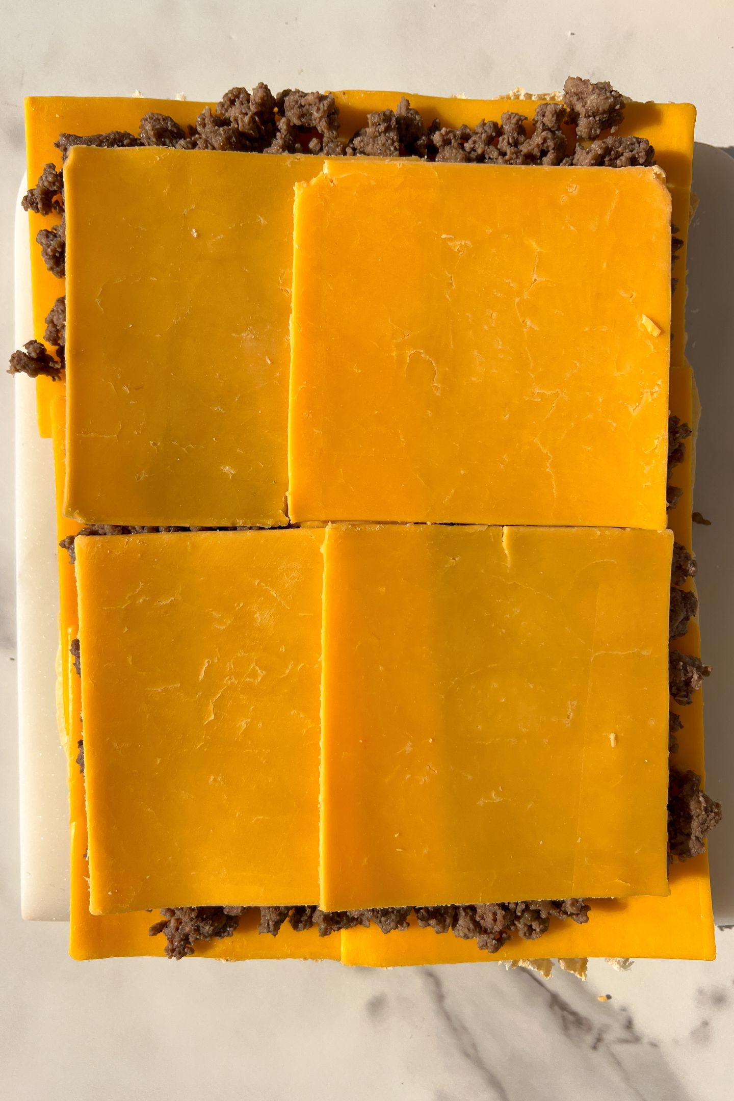 Cheddar cheese slices on top of the cooked ground beef.