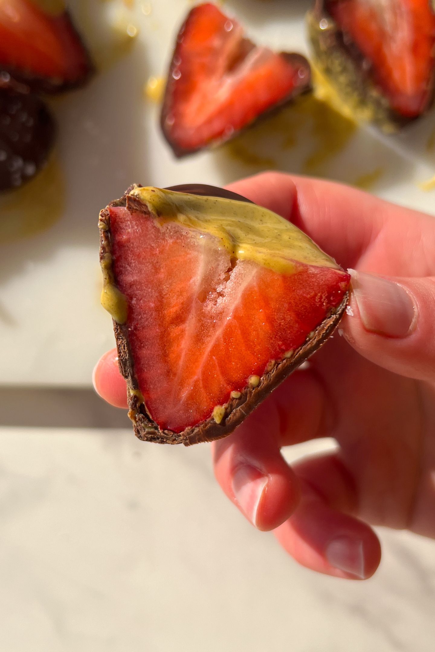 Holding a Pistachio Chocolate Strawberry cut in half in my hand.
